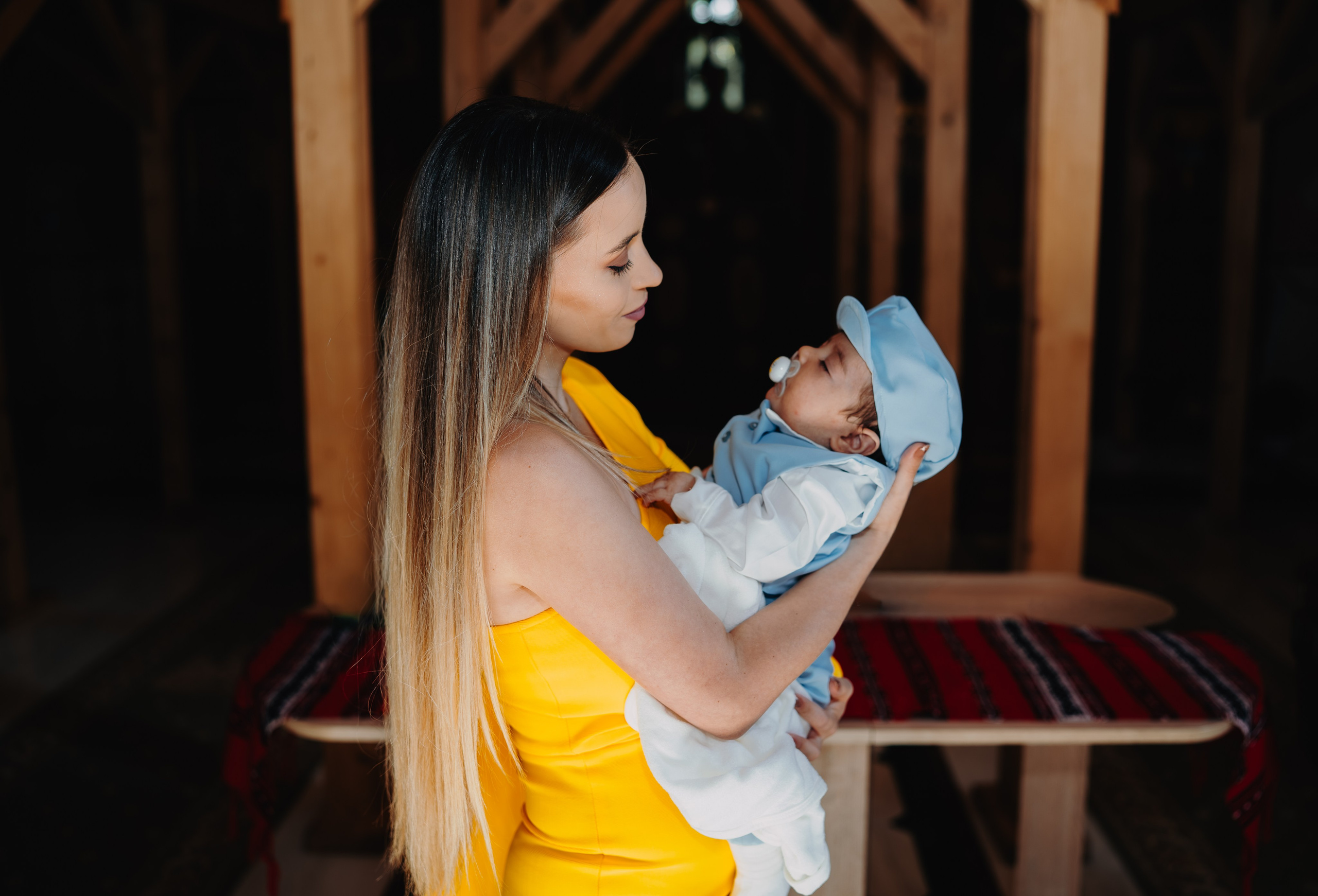 Cadru intim: mama lui Arthur Mihail îl ține aproape în brațe după botez, privindu-l cu o iubire profundă și liniștită. O imagine a conexiunii și mândriei materne în prima zi de creștin a fiului său.