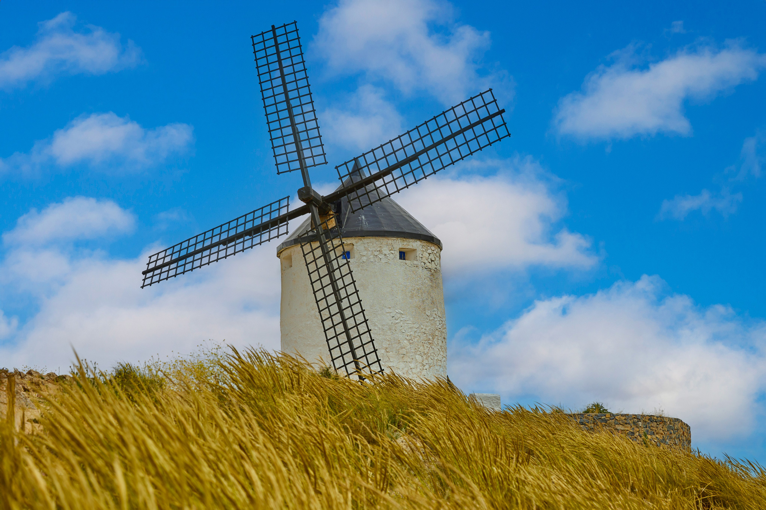 Molino histórico en Consuegra, Castilla-La Mancha, rodeado de trigo dorado y cielo azul