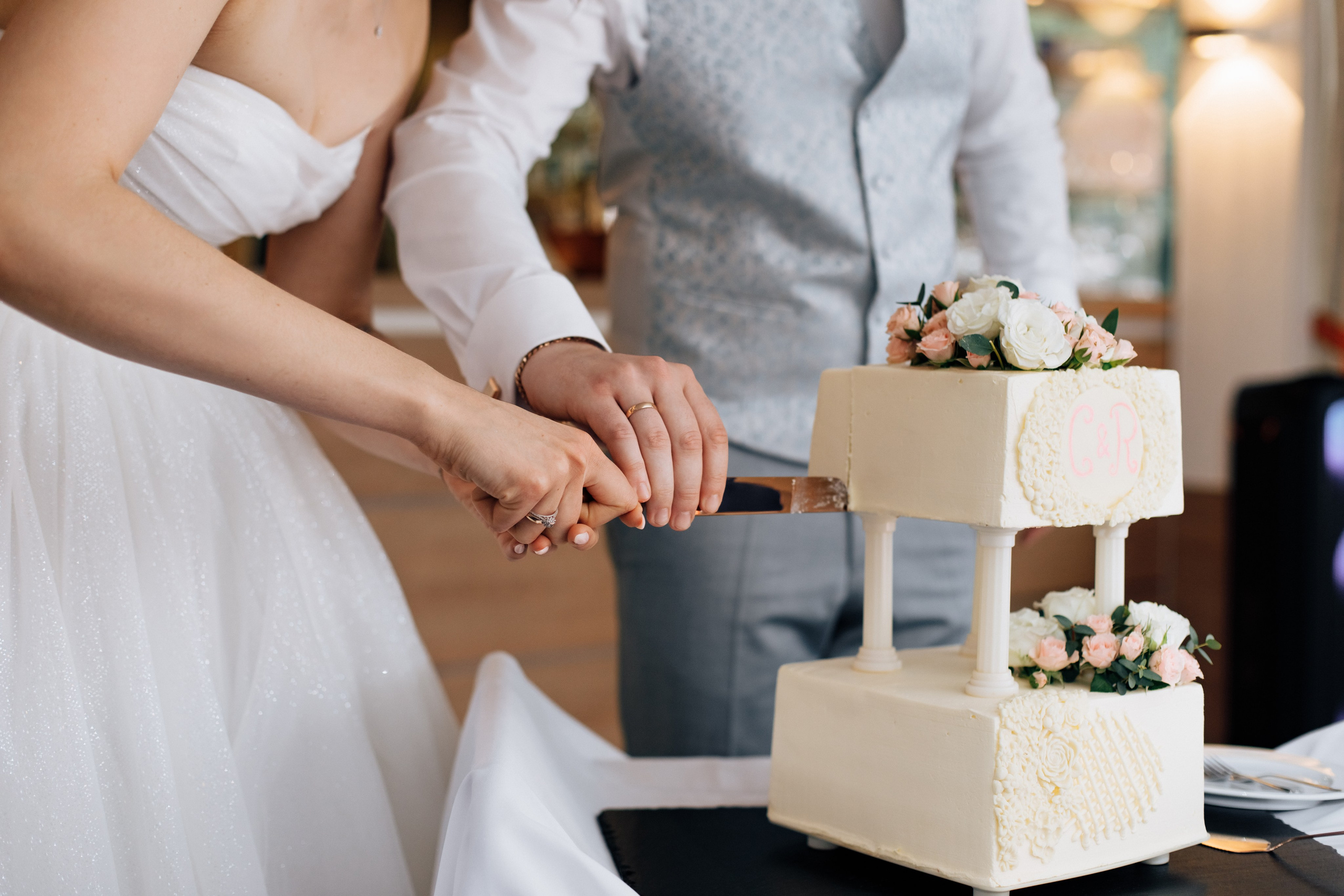 Die Hände des Brautpaars schneiden gemeinsam einen wunderschönen Hochzeitstorte an.