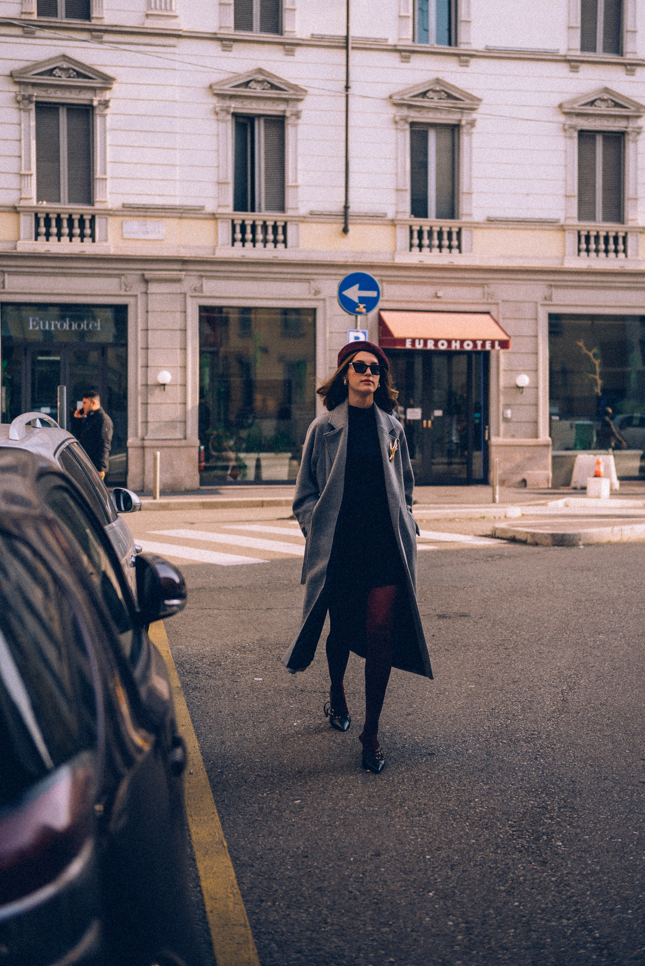 City photography in Milan: a fashionable woman walking through a crosswalk, blending style with urban scenery. Natural light photographer Milan.