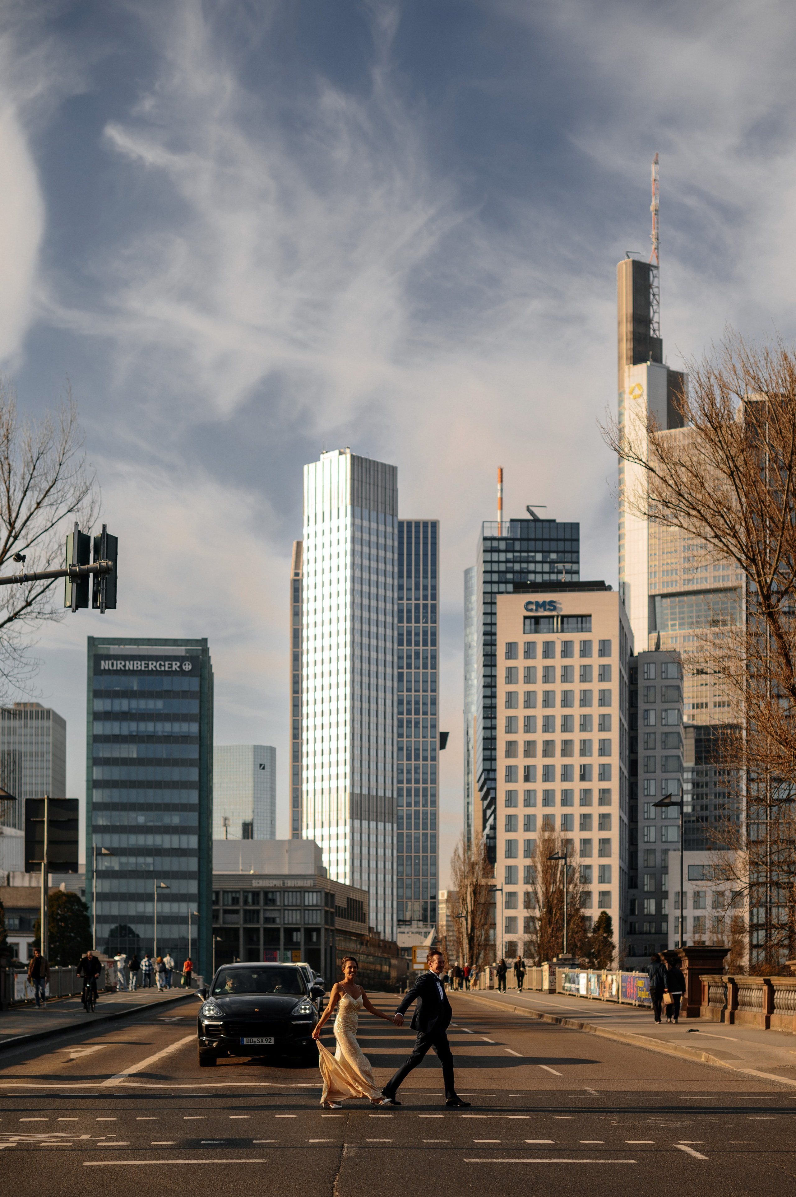 Braut und Bräutigam laufen lachend am Mainufer in Frankfurt, Wolkenkratzer im Hintergrund