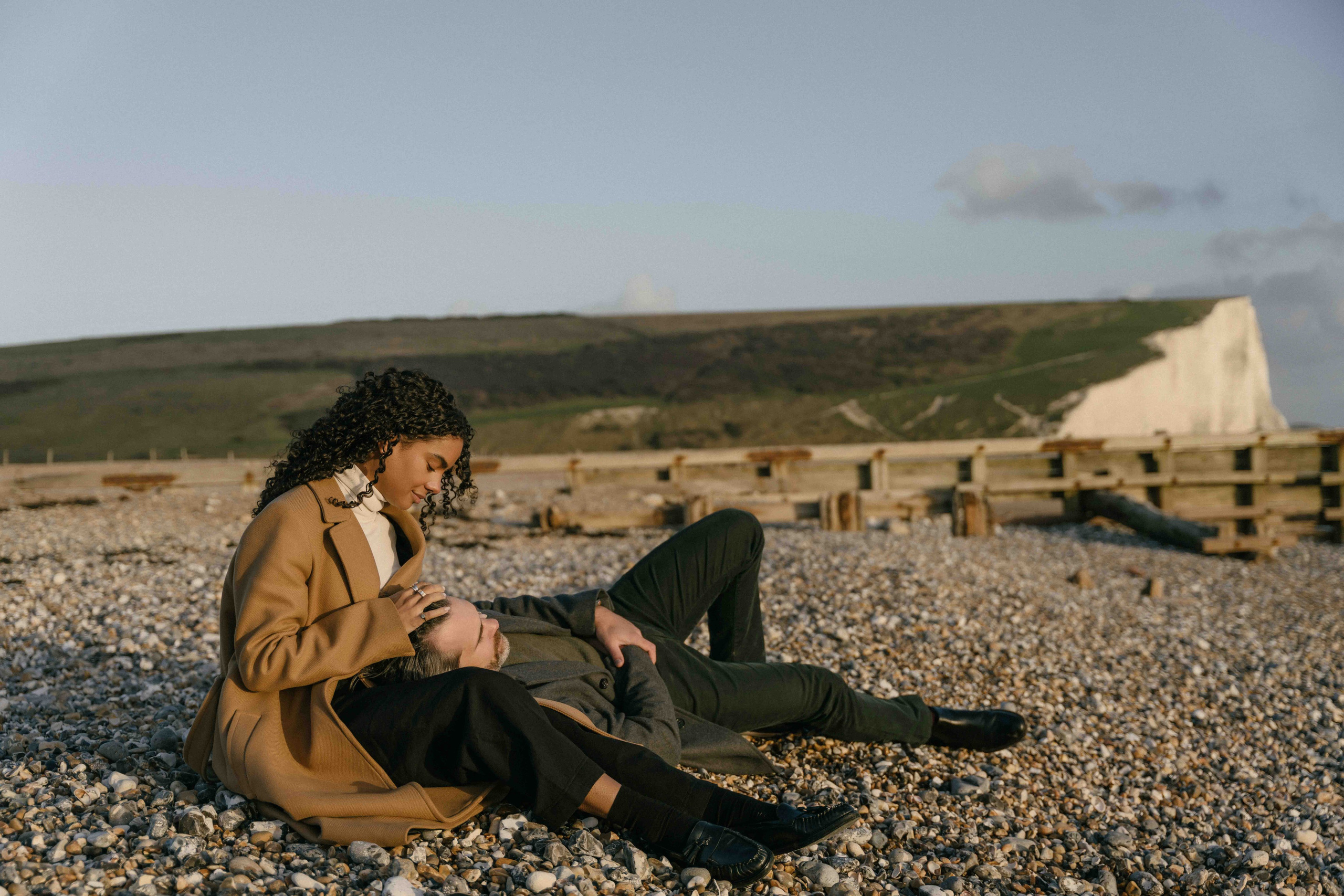 couple sitting on beach seven sisters engagement session uk