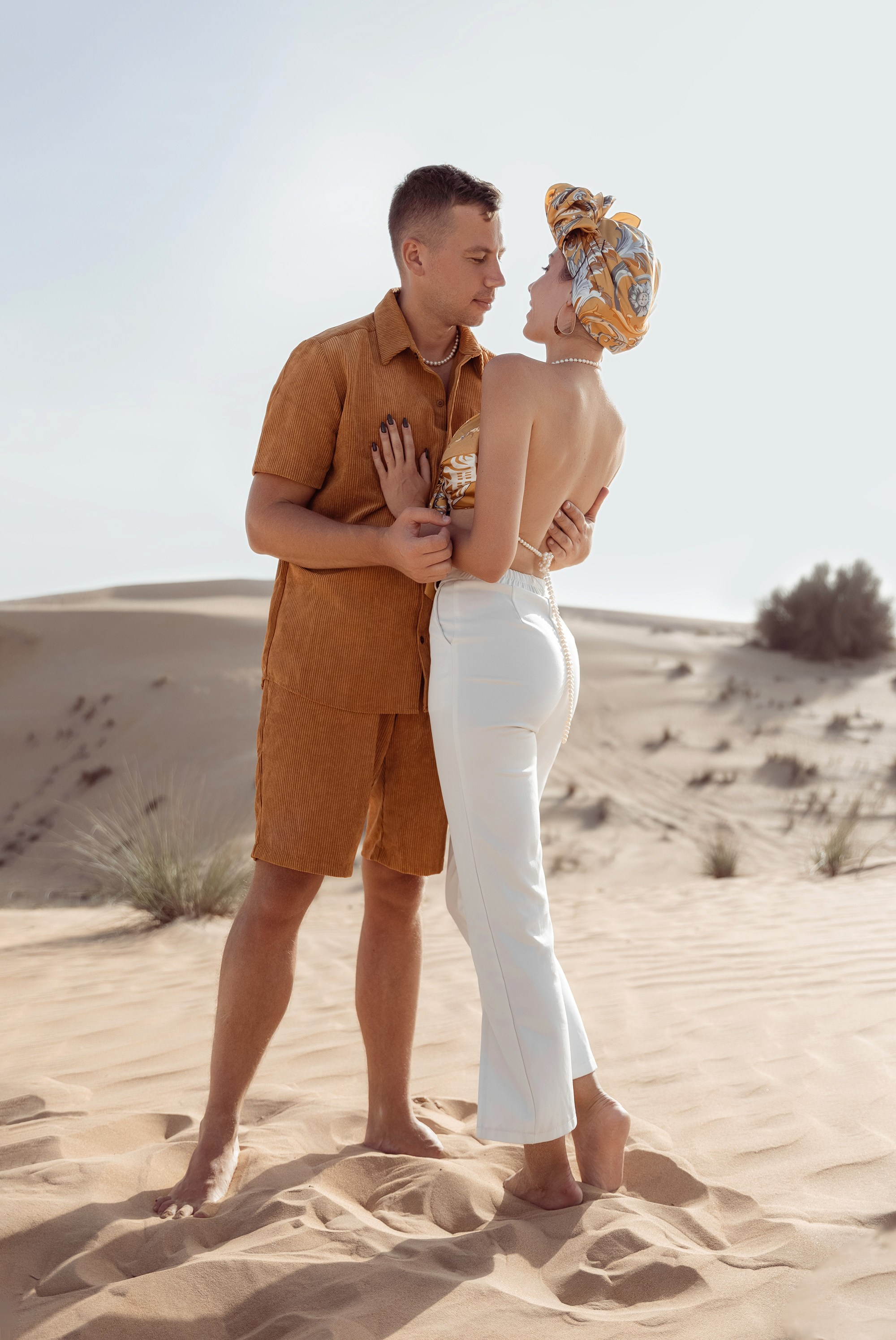 A couple connects in the desert, playfully interacting and holding each other, with the serene beauty of the landscape enhancing the moment. Dubai, United Arab Emirates