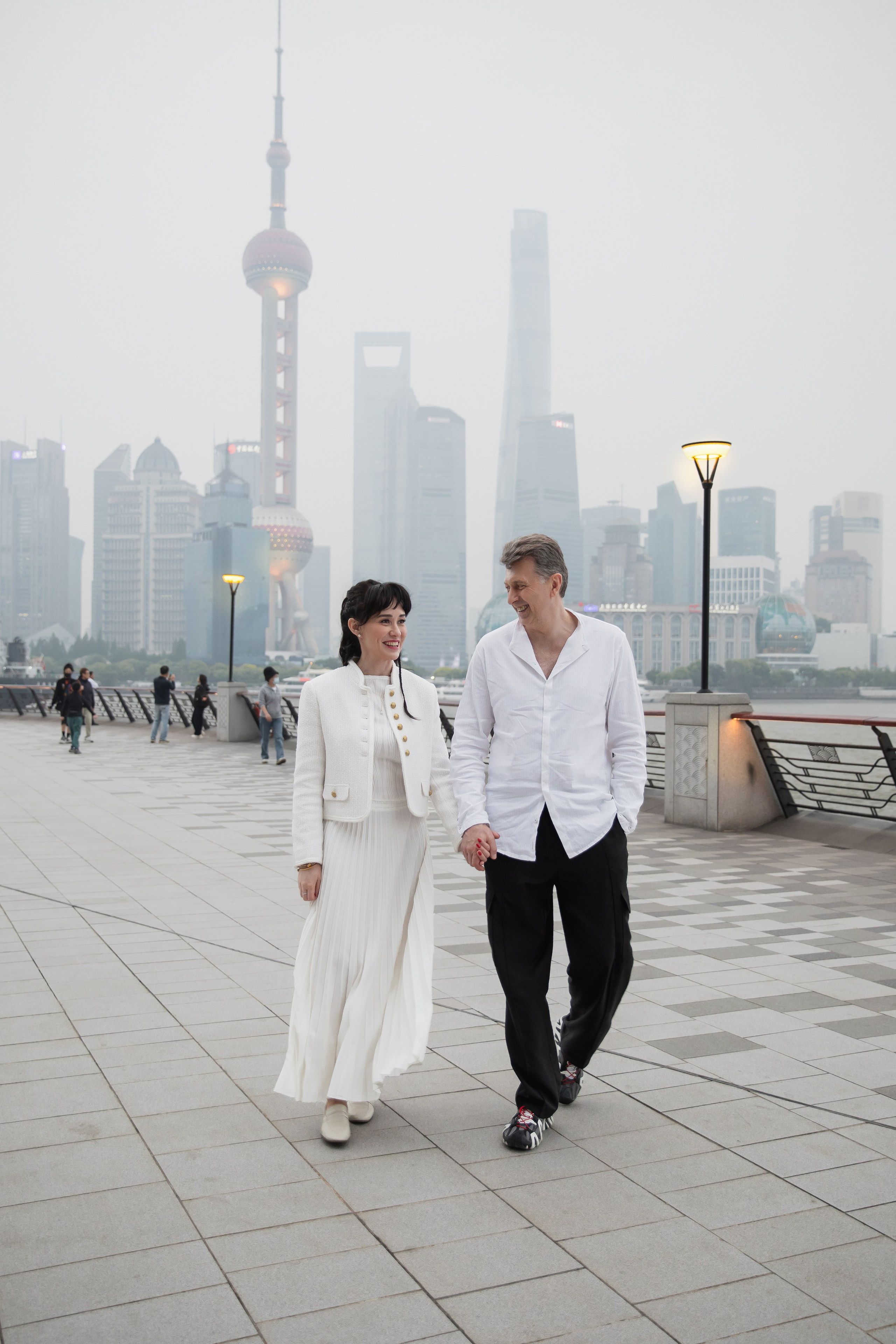 Влюбленные гуляют по набережной The Bund с видом на башню Цзиньмао