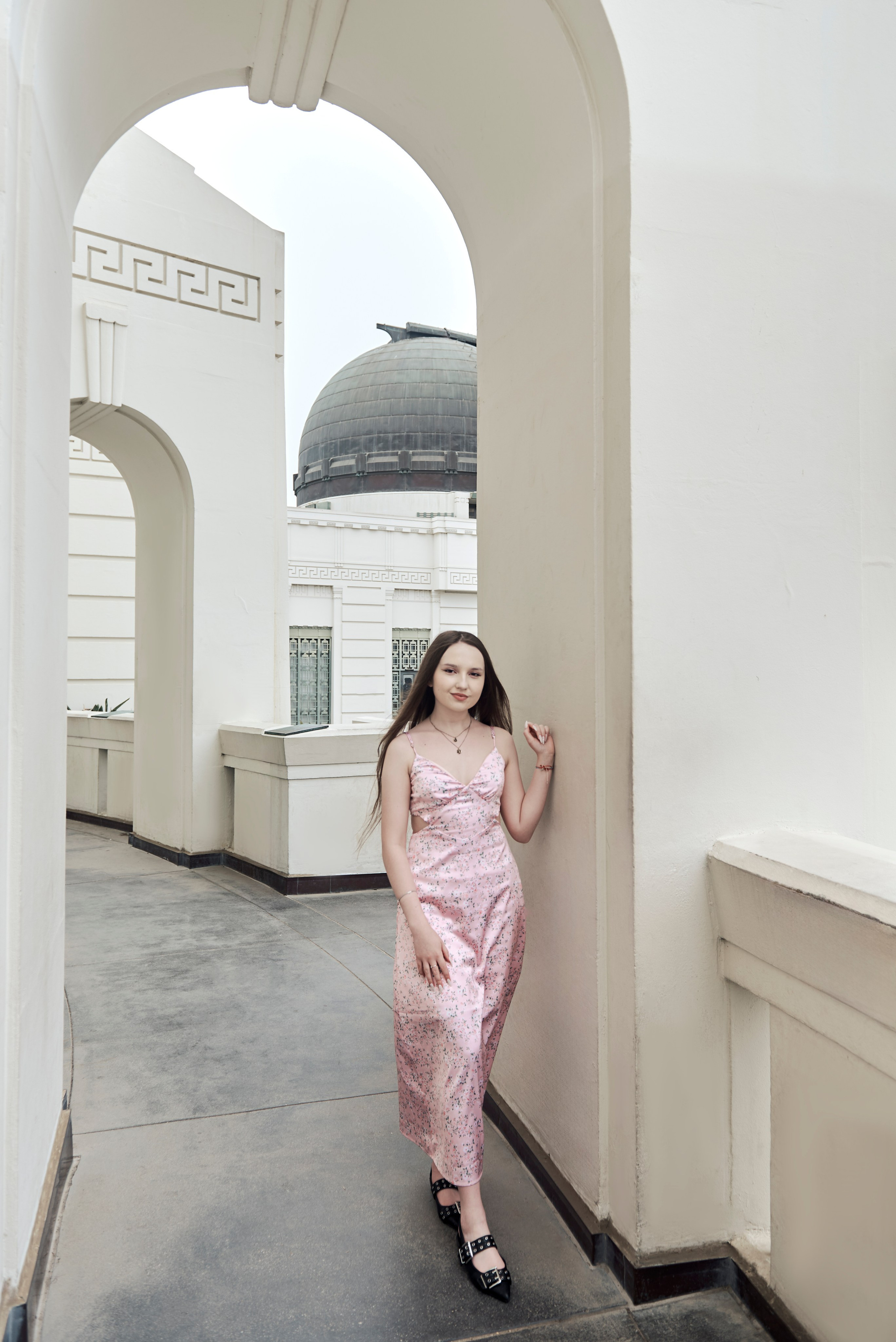 Graduate in a cap and gown with a congratulatory bouquet in a Los Angeles park