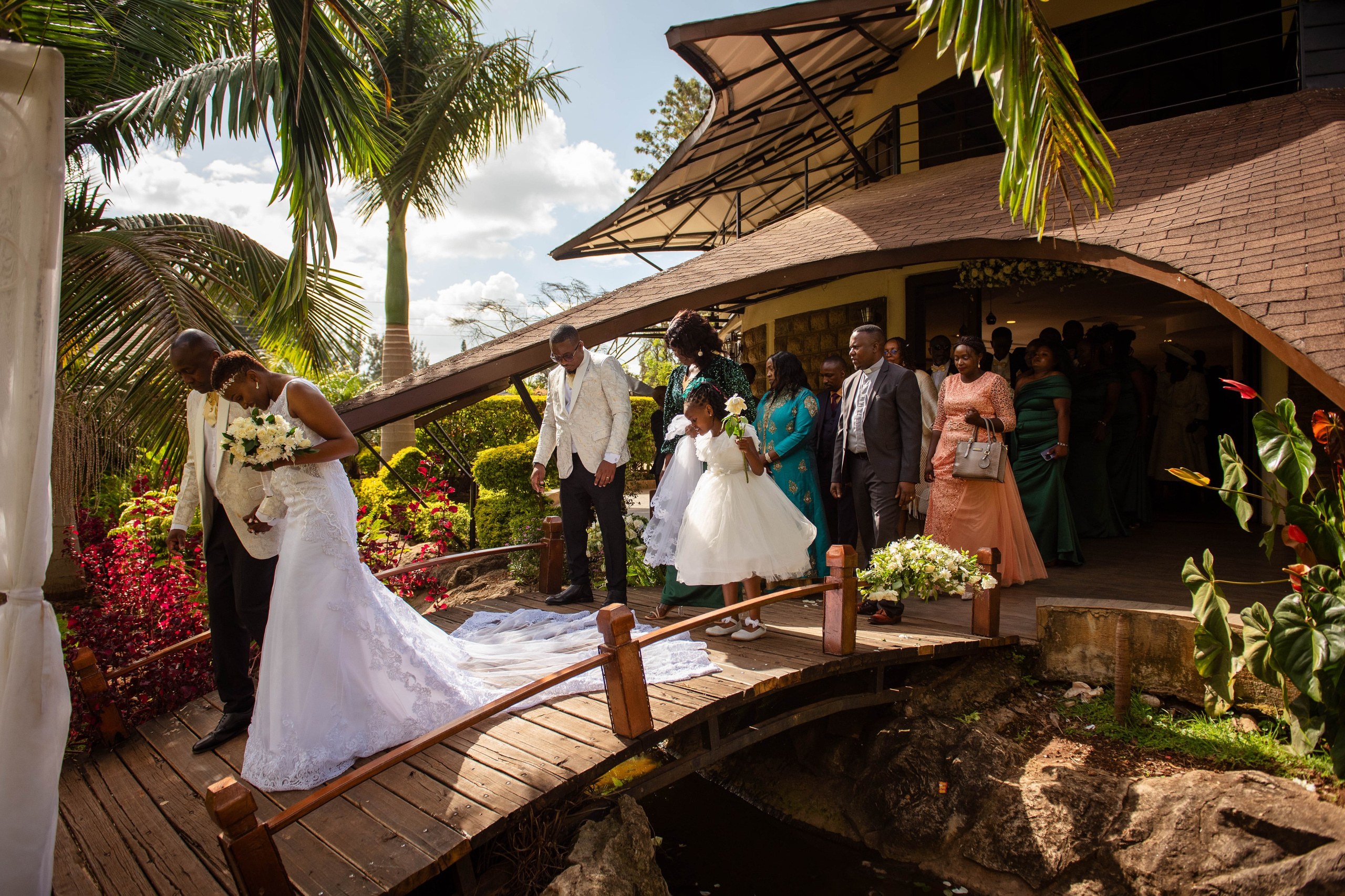 A wide shot of a bride and groom leading guests from the church to the reception area, in Nairobi