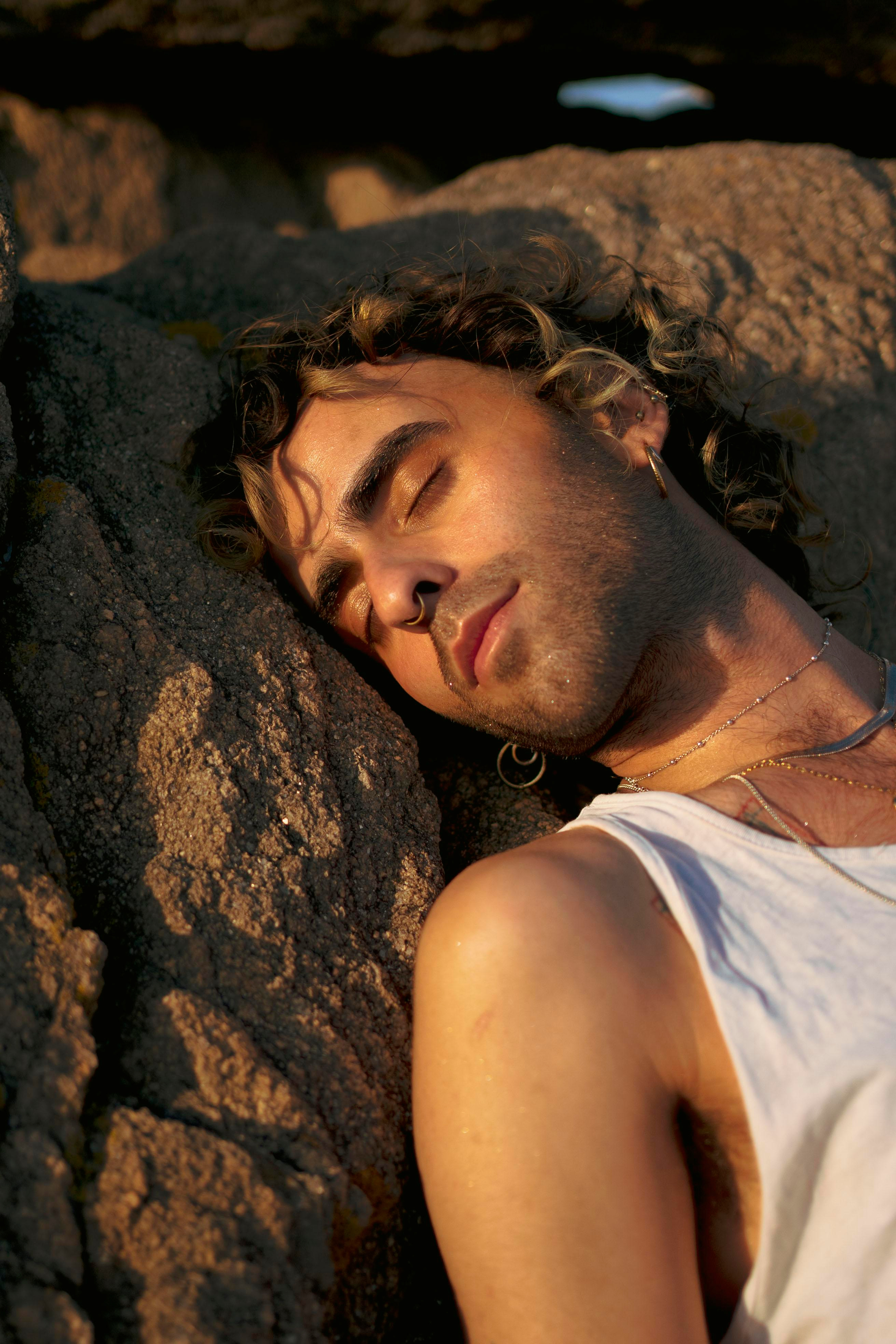 LGBTQ+, LGBT portrait of a beautiful person with makeup, a white tank top, and curly hair.