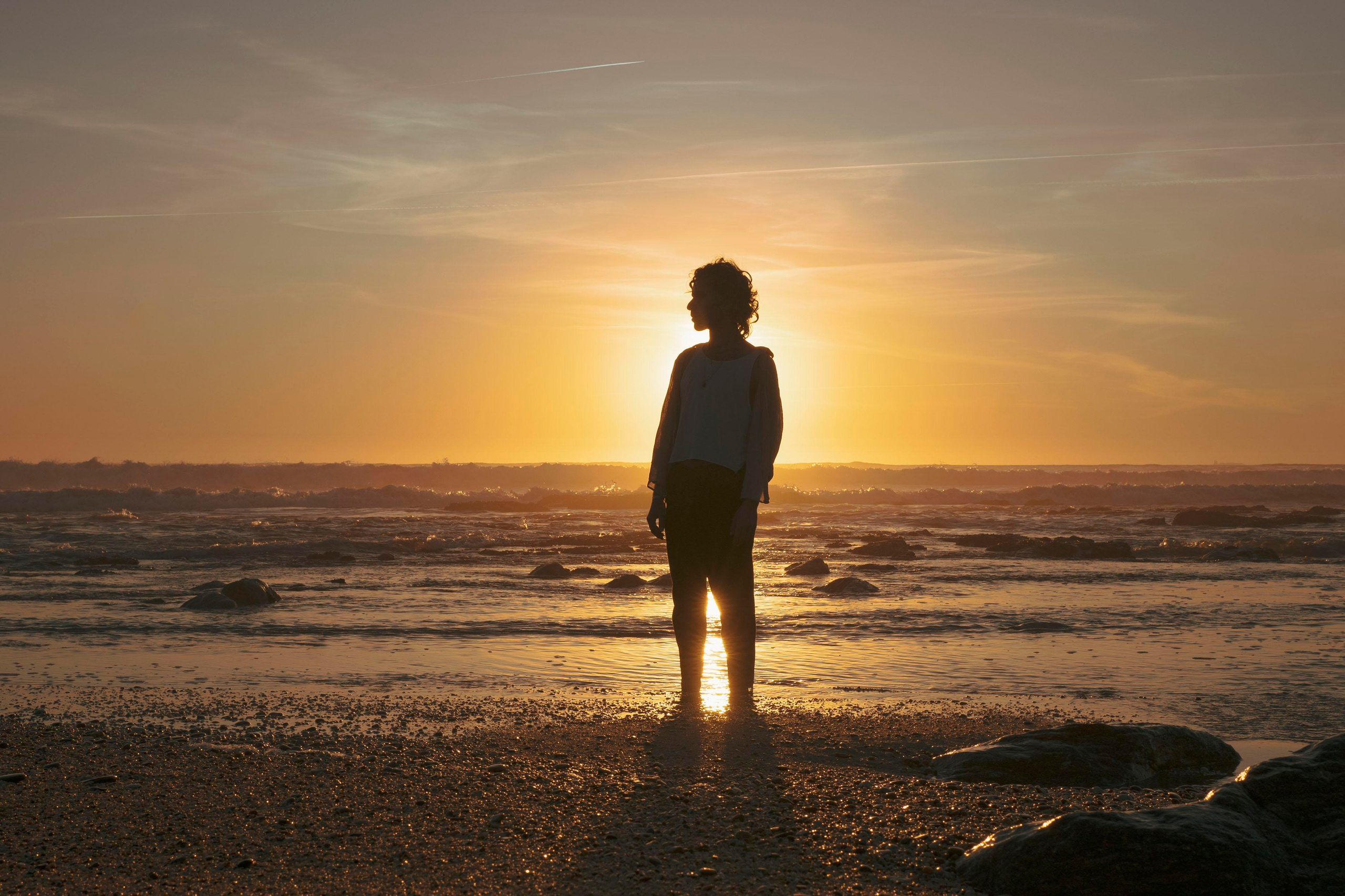 Silhouette of a person with a sunset sky in the background.