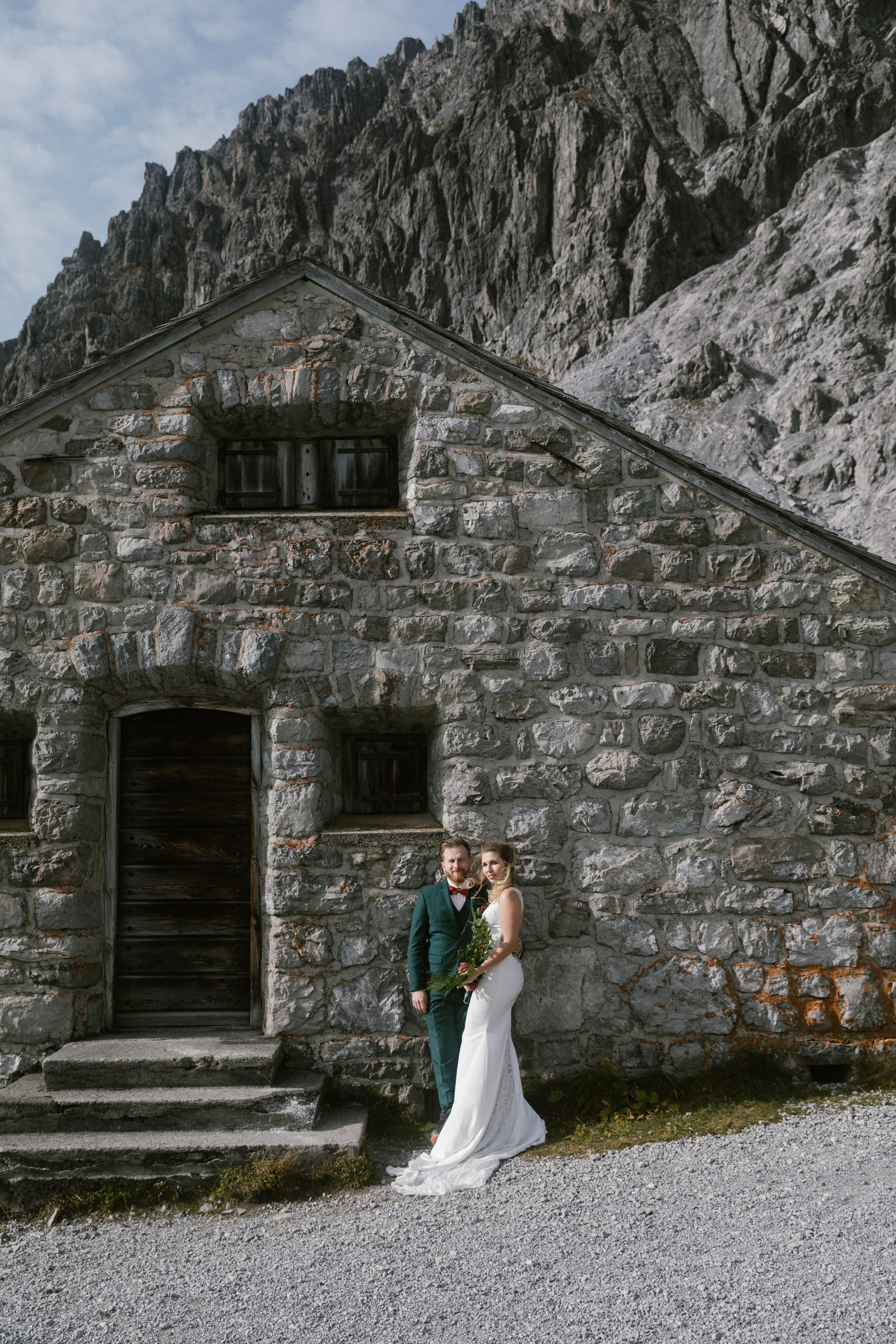 Braut und Bräutigam vor alpiner Steinhütte bei Hochzeitsfotos