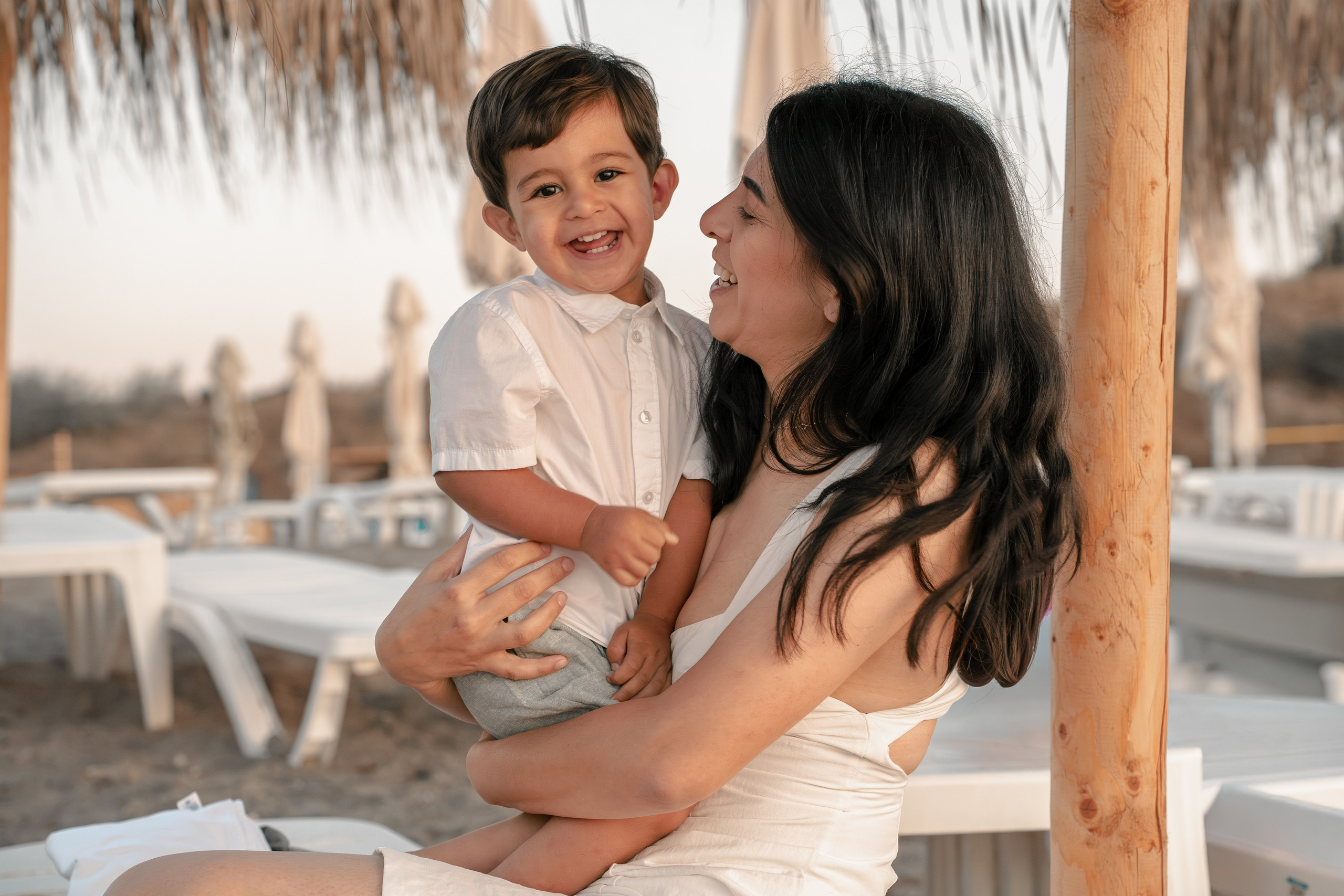 baietel in bratele mamei, pe plaja