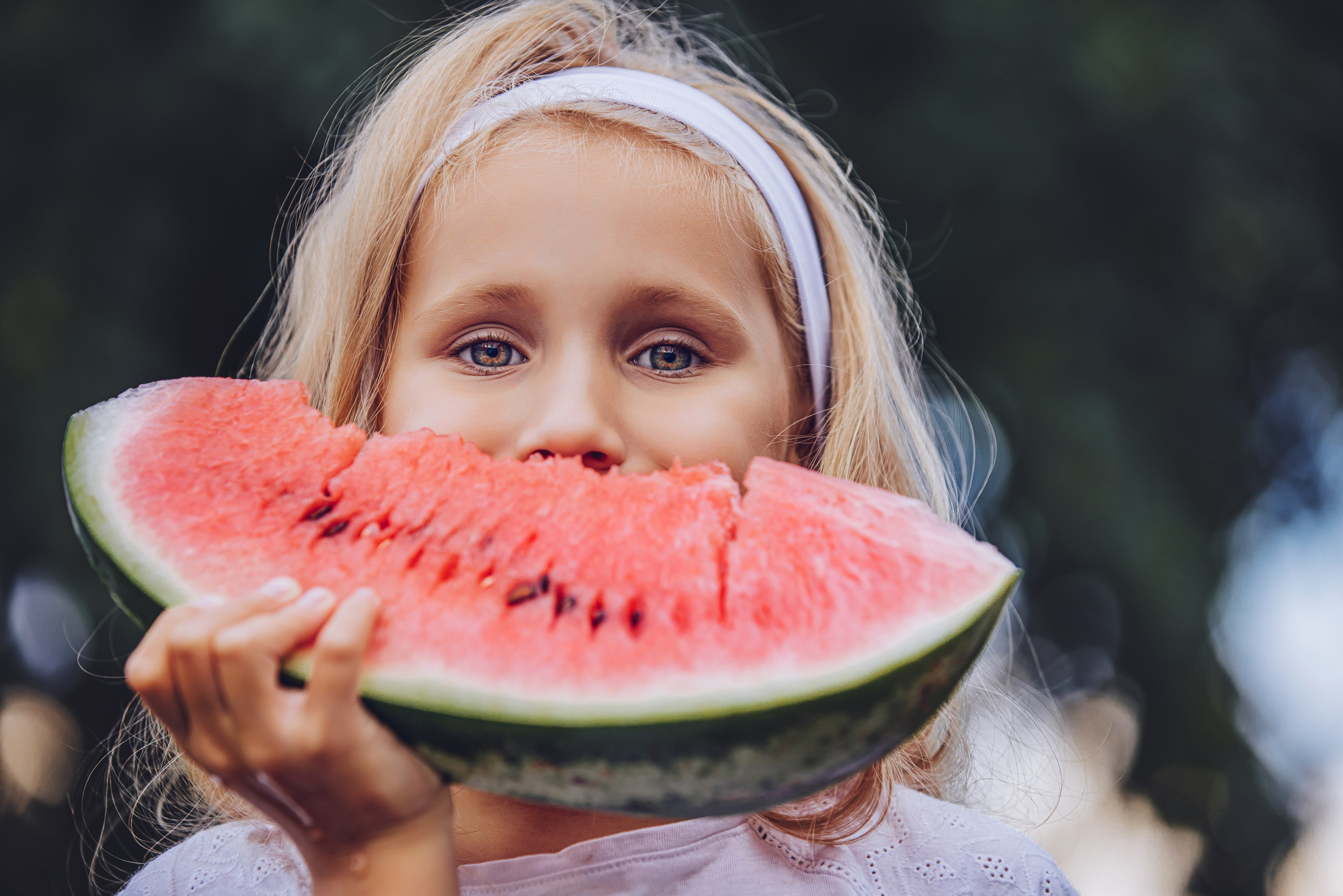 Fillette blonde croquant une tranche de pastèque juteuse pendant l'été
