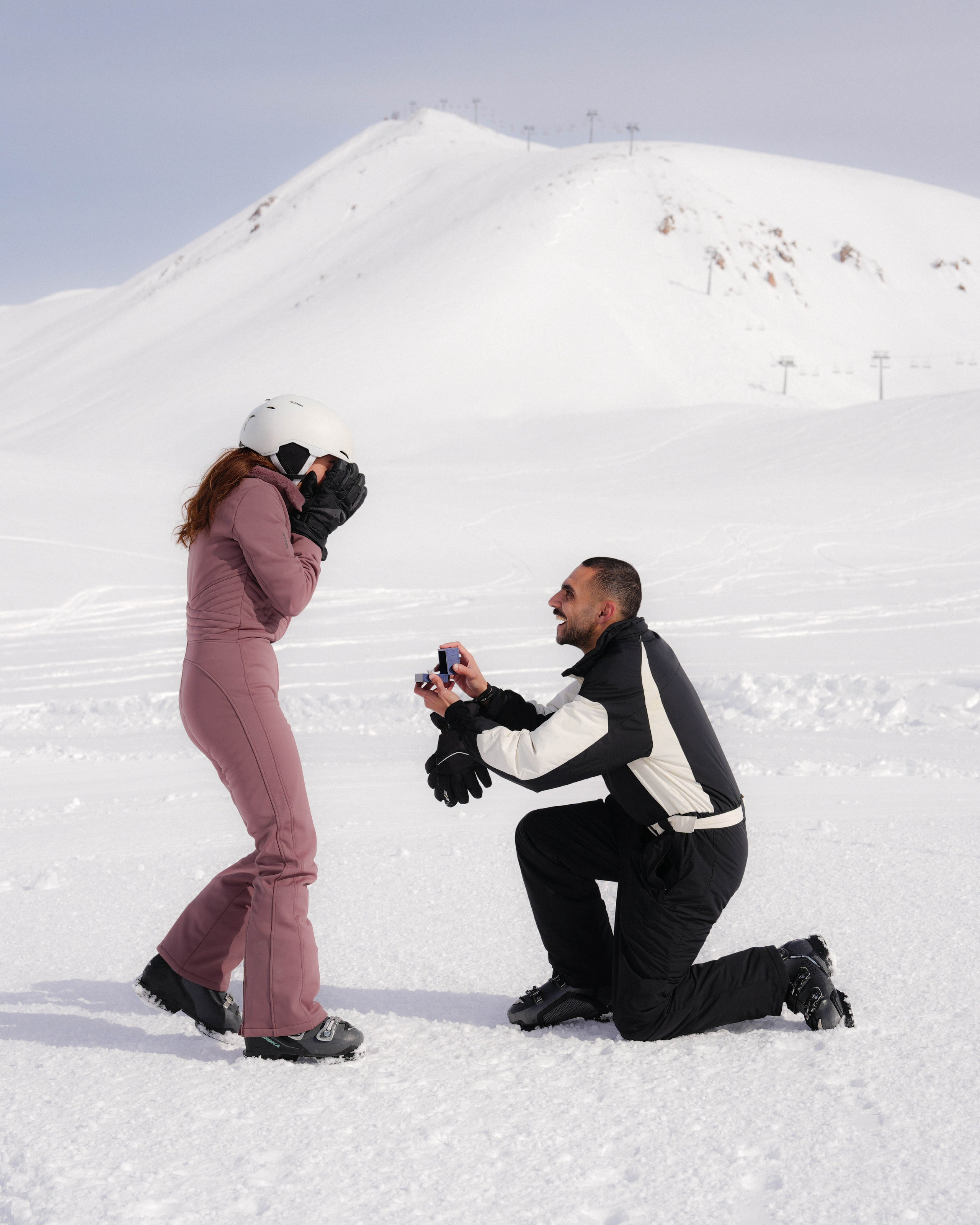 Man proposing on snow in mountain landscape