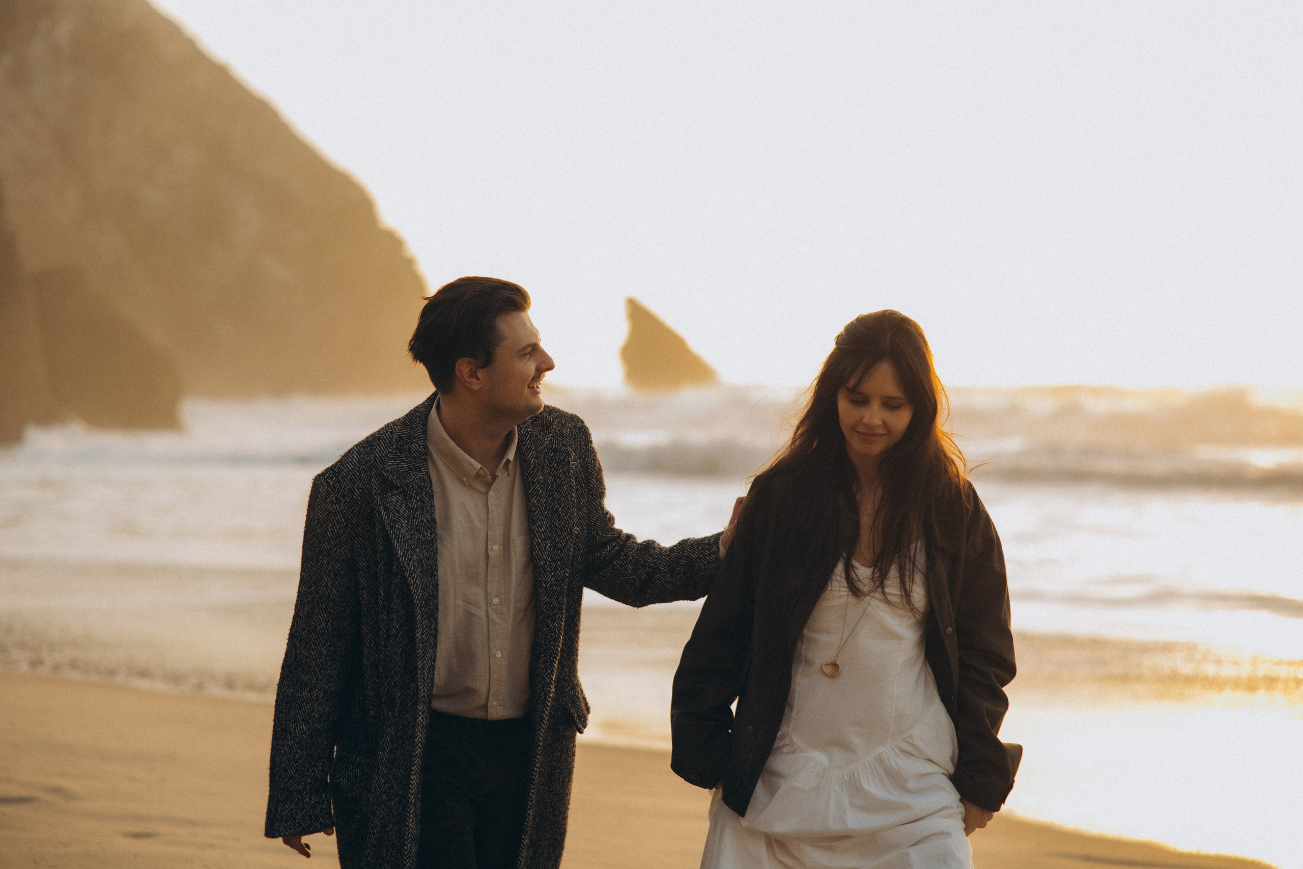 Couple holding hands and walking through a picturesque coastline in Portugal.