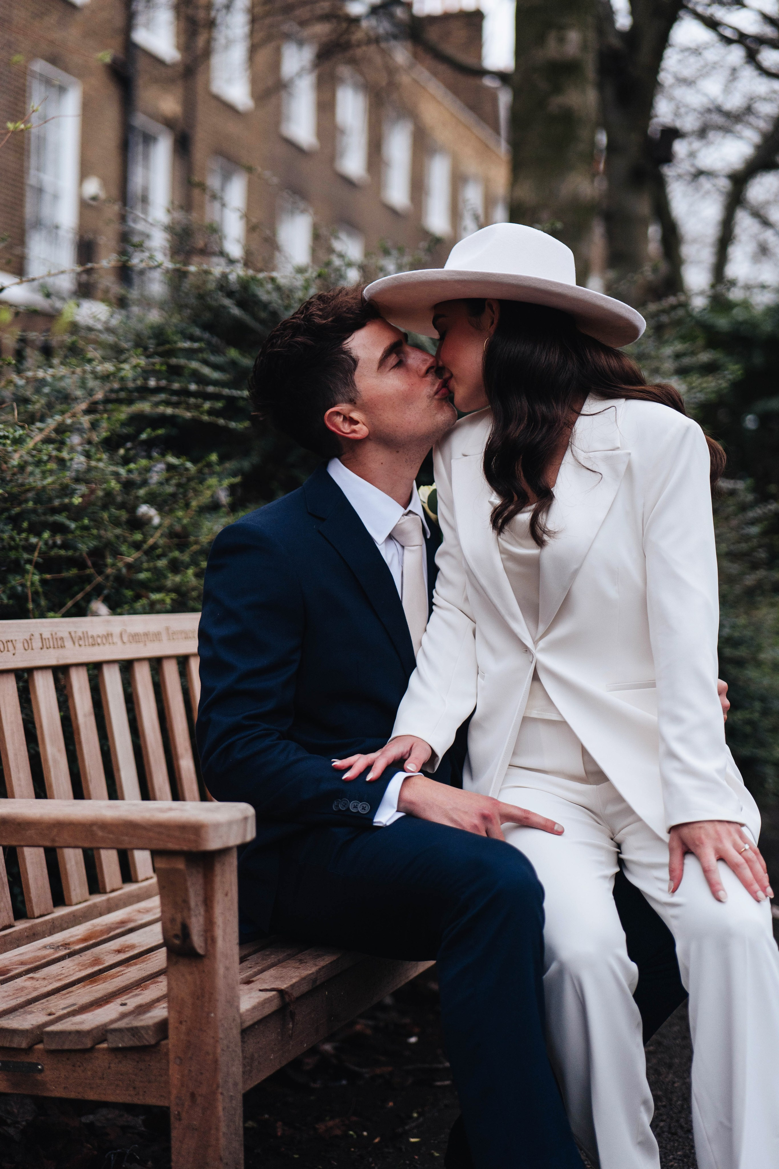 Stylish wedding in Islington, white women costume and white hat, sitting on a bench