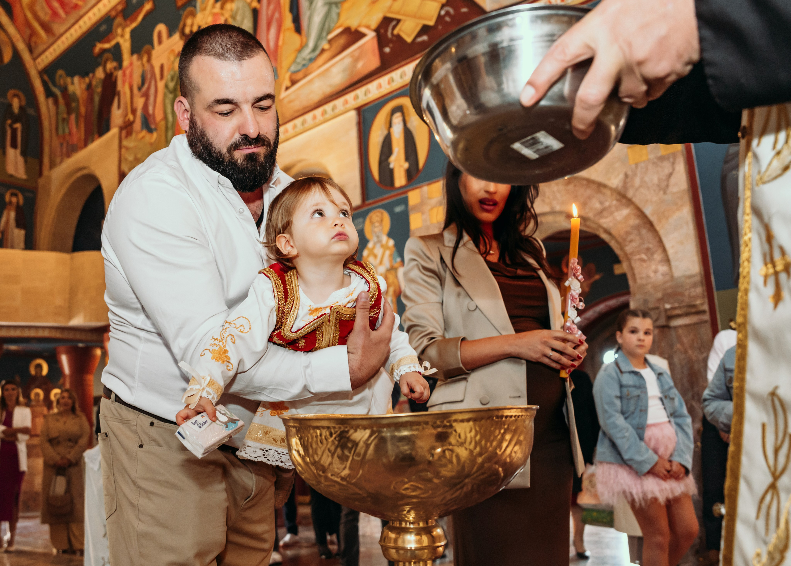 Svestenik poliva bebu na krstenju