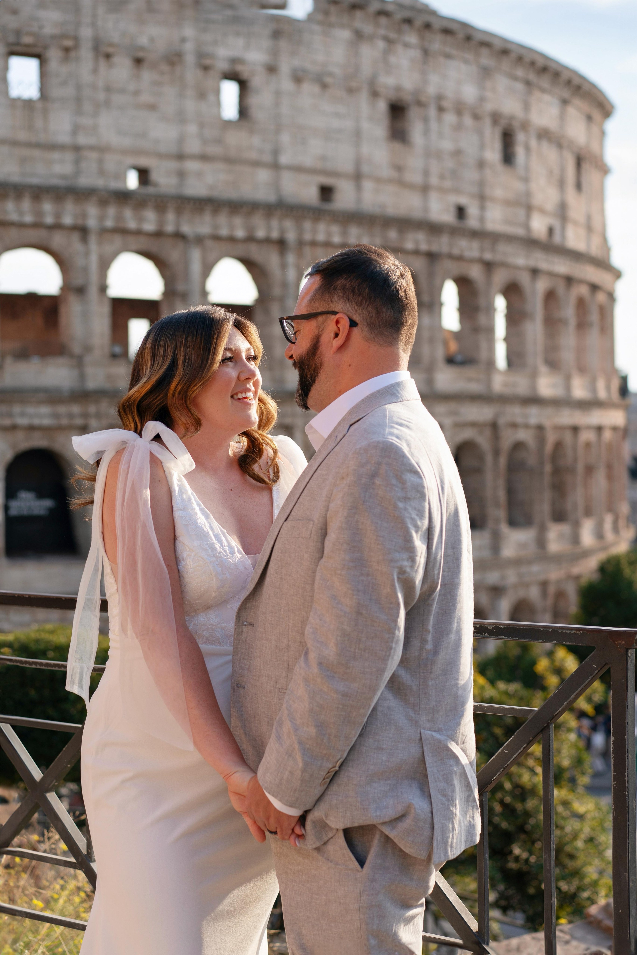 groom and bride looking at each other and smiling with colosseum on the background