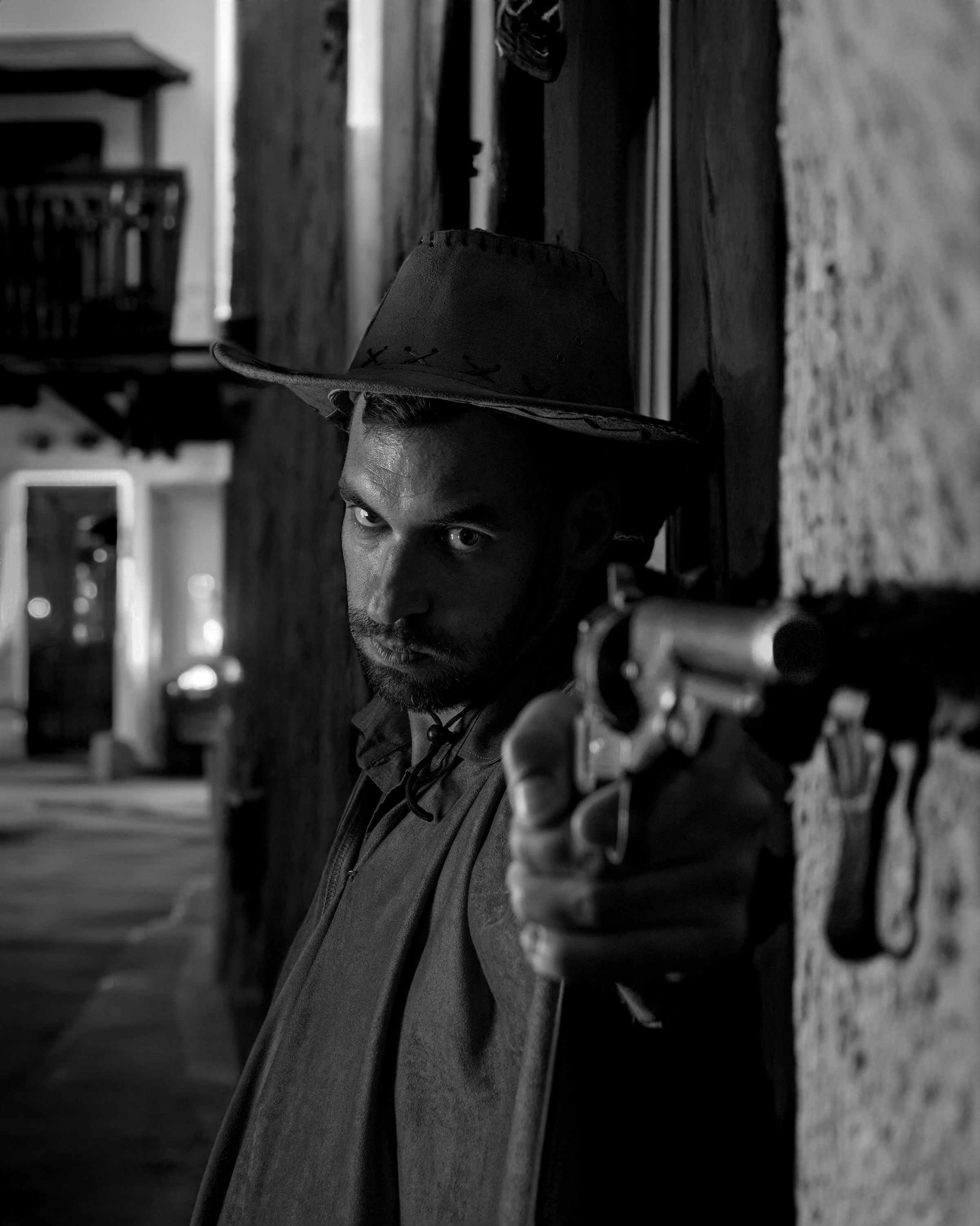 Witd West Street-style black and white portrait of a man pointing a gun toward the camera