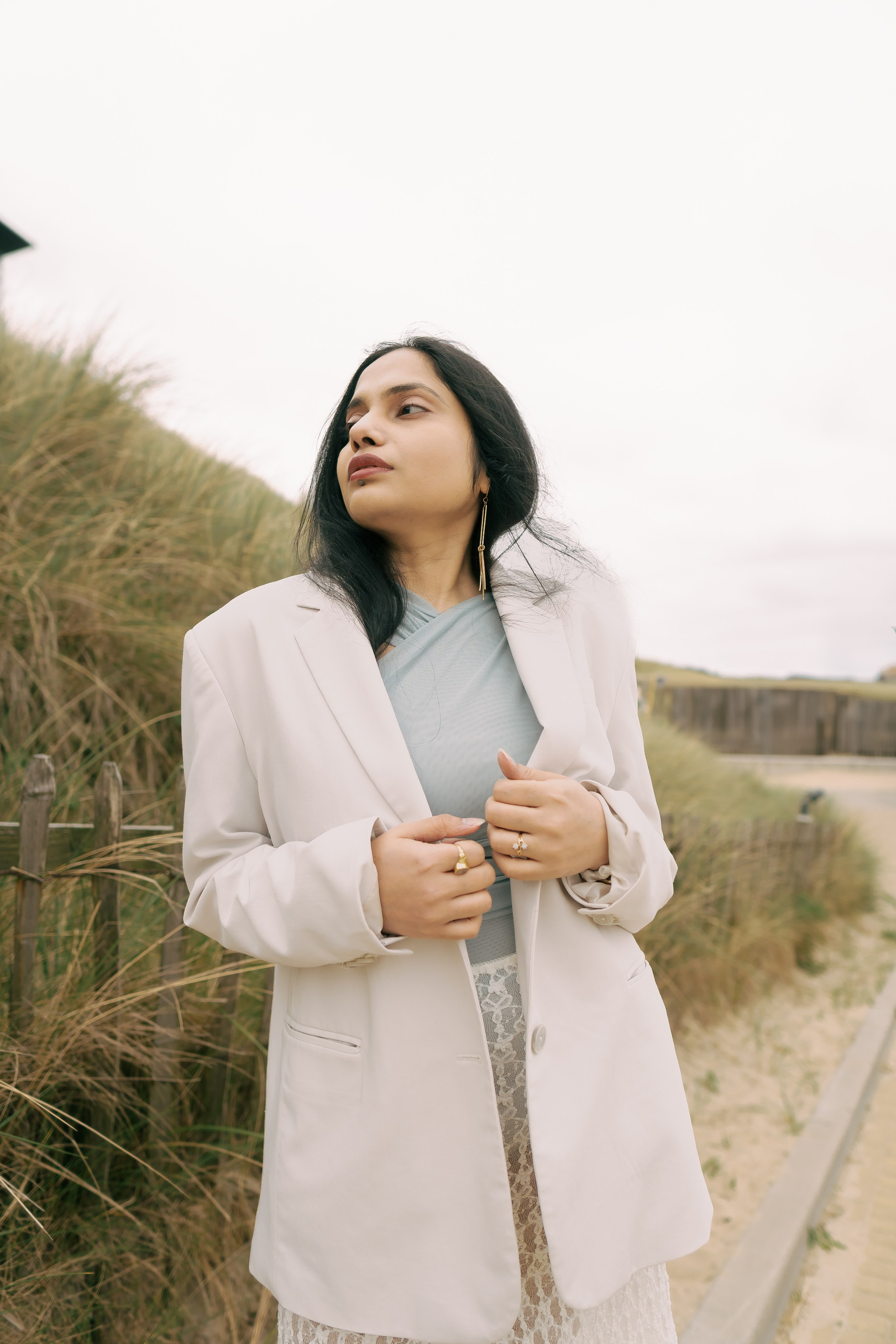 Fashion photoshoot in dunes with lace skirt and white blazer