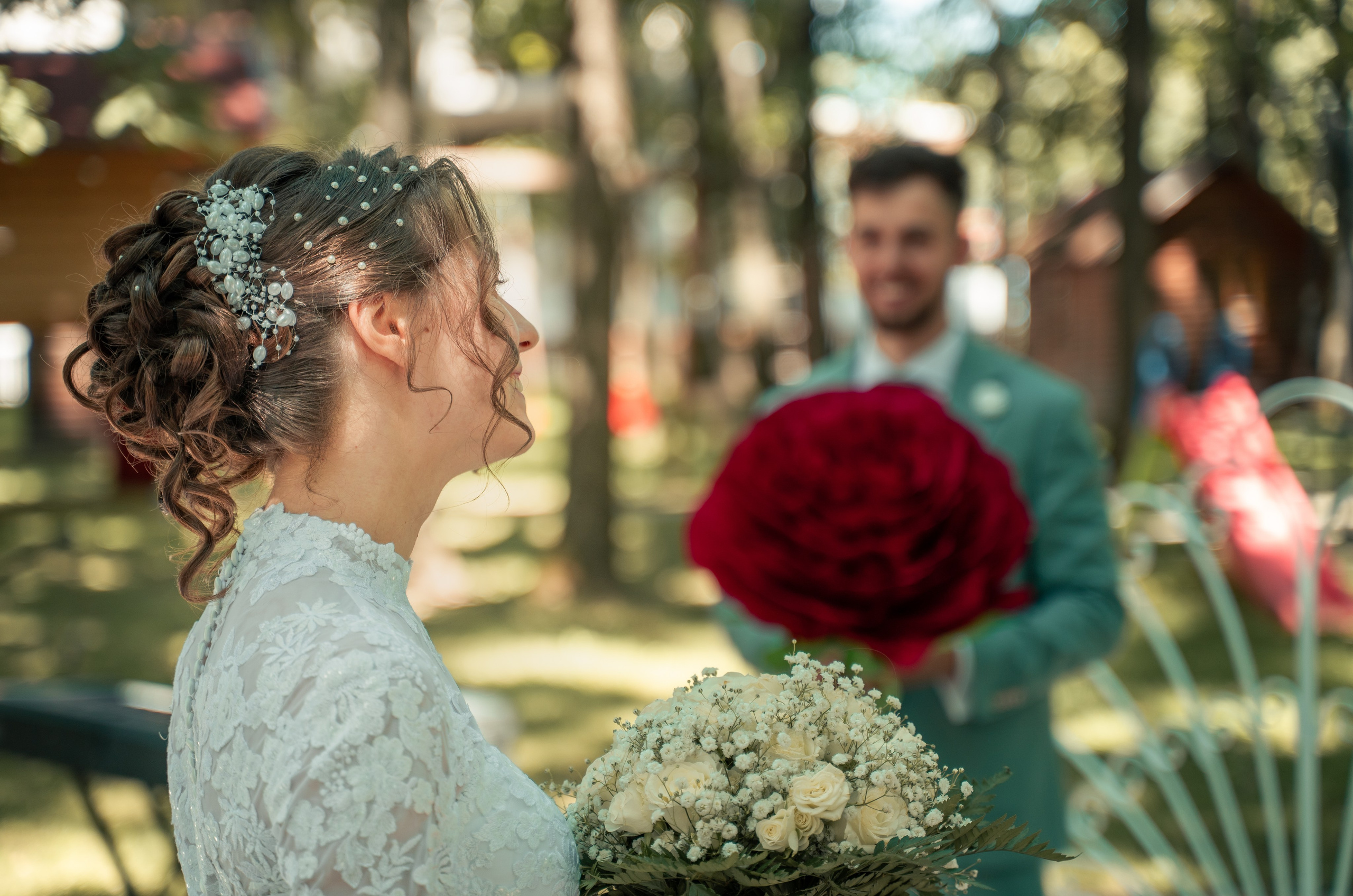 Mireasă cu buchet alb de gipsofila și mire ținând un trandafir roșu uriaș, moment haios nuntă în aer liber, fotograf profesionist București, incadru.ro.