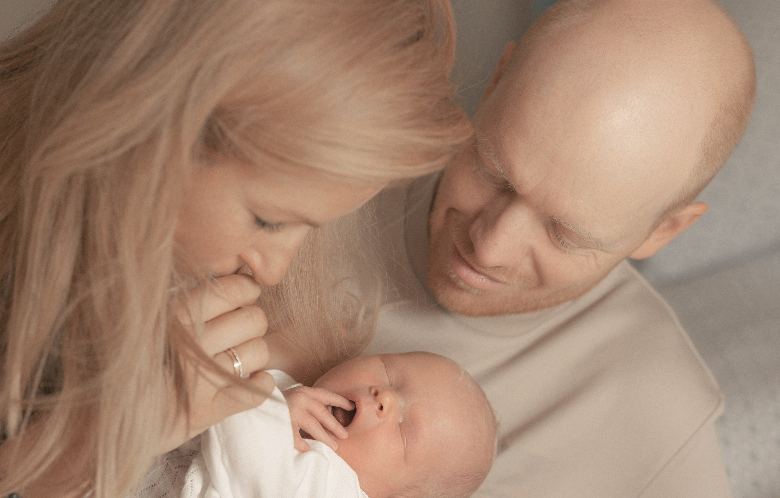 Eltern beugen sich zärtlich über ihr Baby – emotionale Szene aus einem Babybauch- und Familien-Fotoshooting in Salzburg