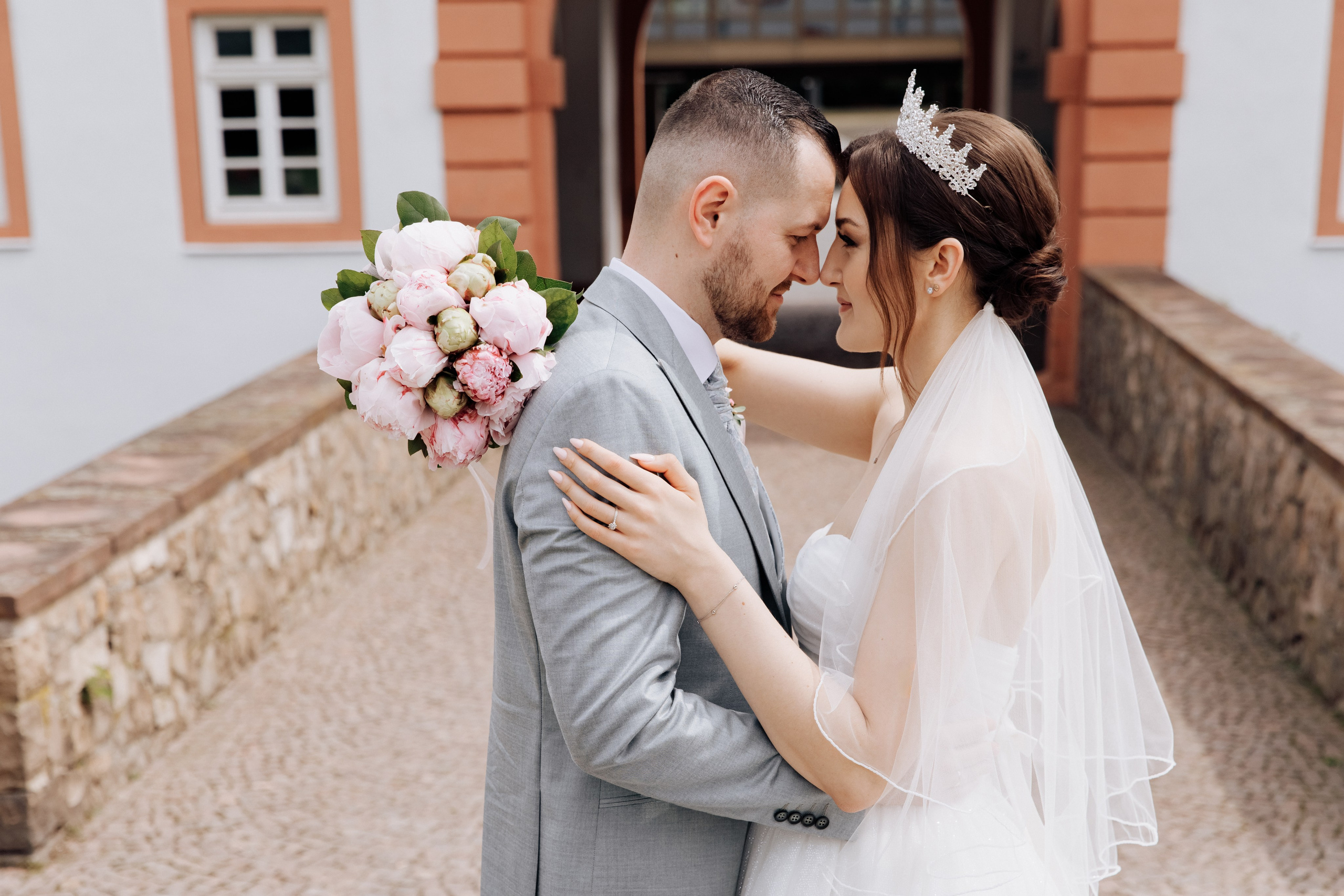 Der Bräutigam und die Braut umarmen sich vor dem Schloss Heusenstamm.