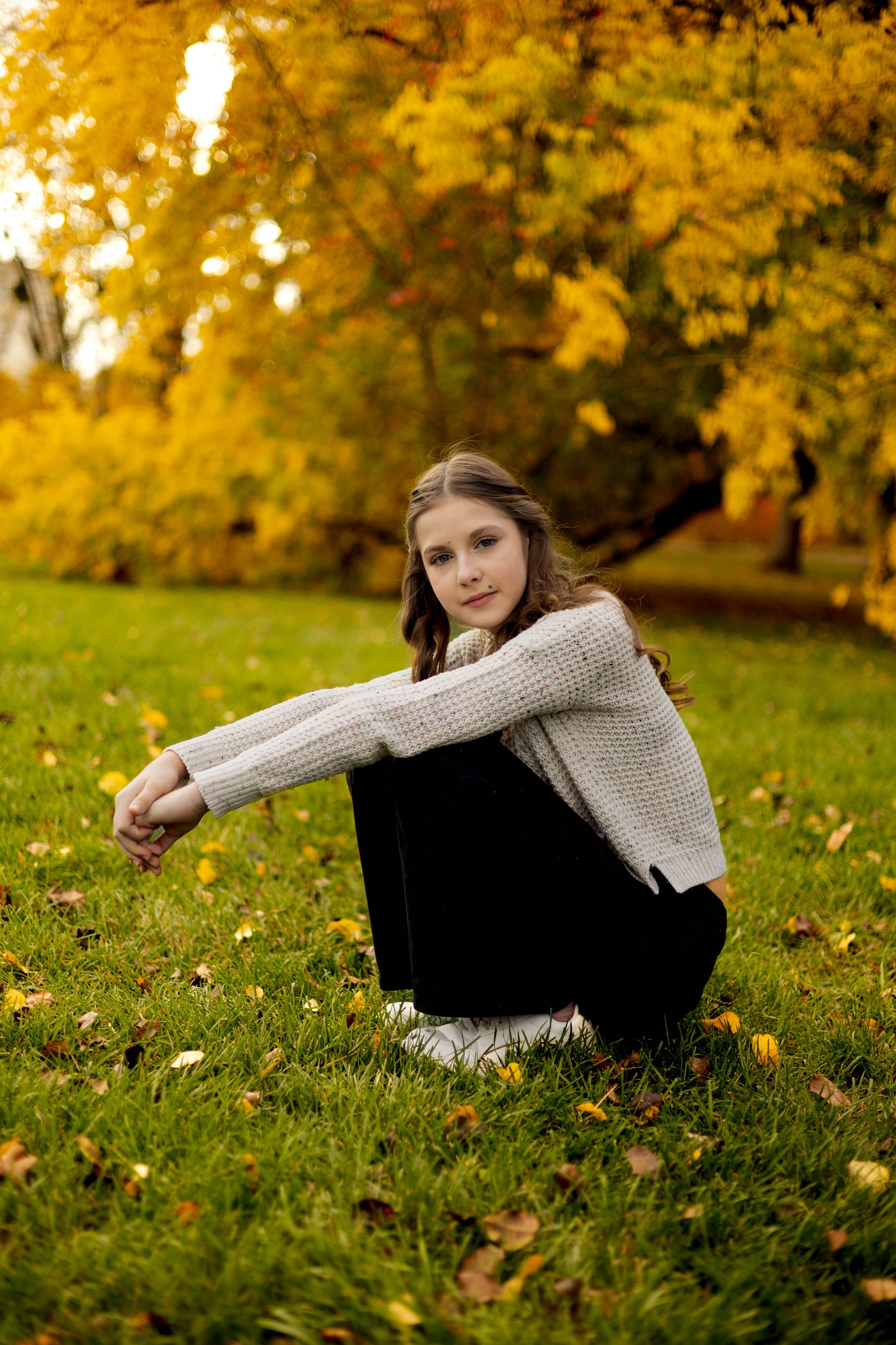 Портрет девушки в лучах осеннего солнца на фоне деревьев.