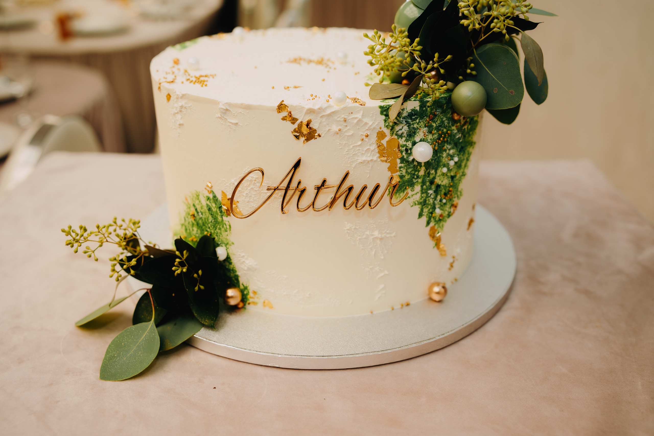 Tortul elegant și decorat pentru botezul lui Arthur Mihail, așezat pe masa festivă la Restaurantul Monden din Bârlad. Se vede decorul cu numele sau motivele temei.