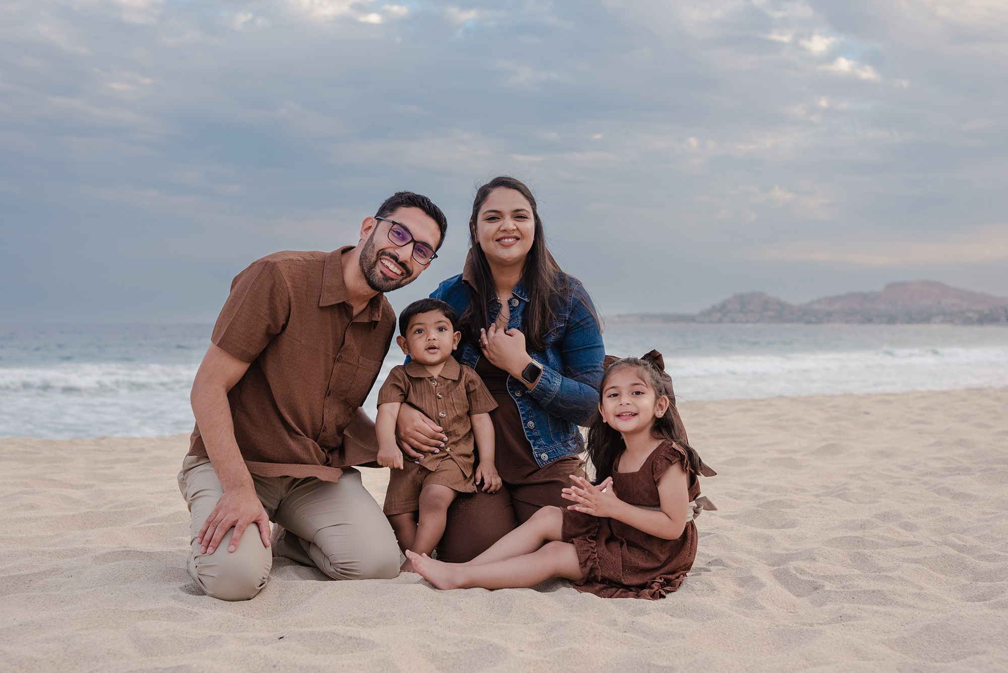 Family of four sitting together on the sand at Hyatt Ziva Los Cabos