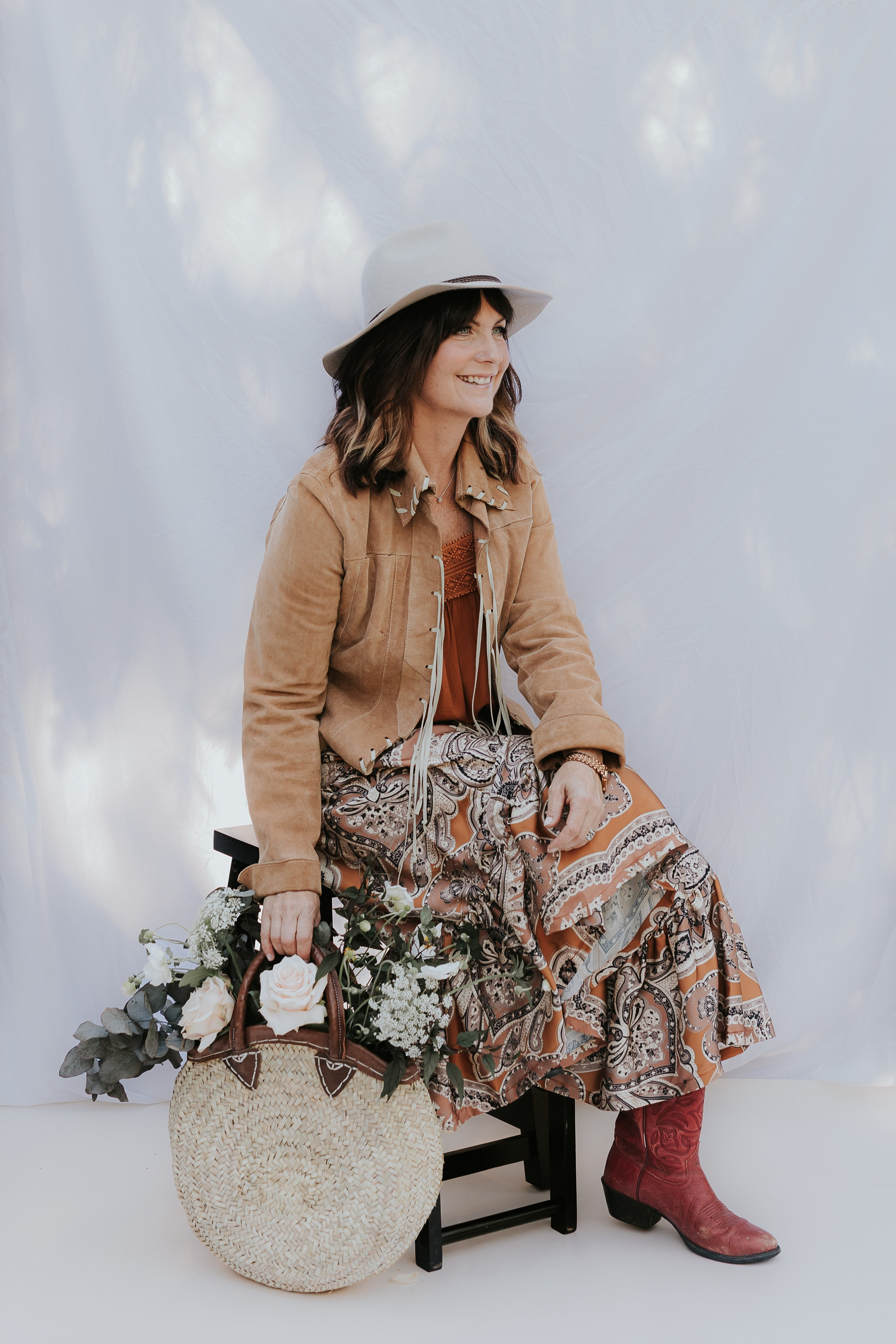 woman looking off camera holding a woven basket of flowers 