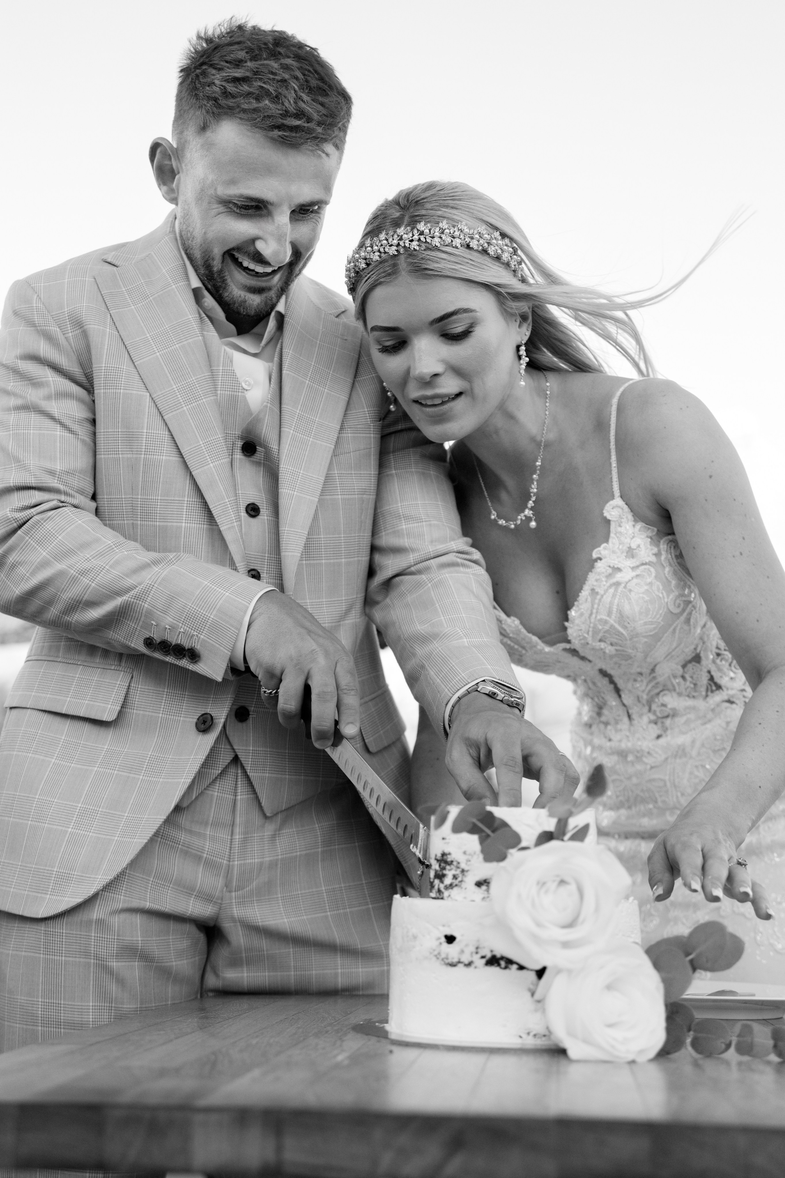 A Groom and a bride are cutting Wedding cake at a rustic bar in Lindos, Greece.