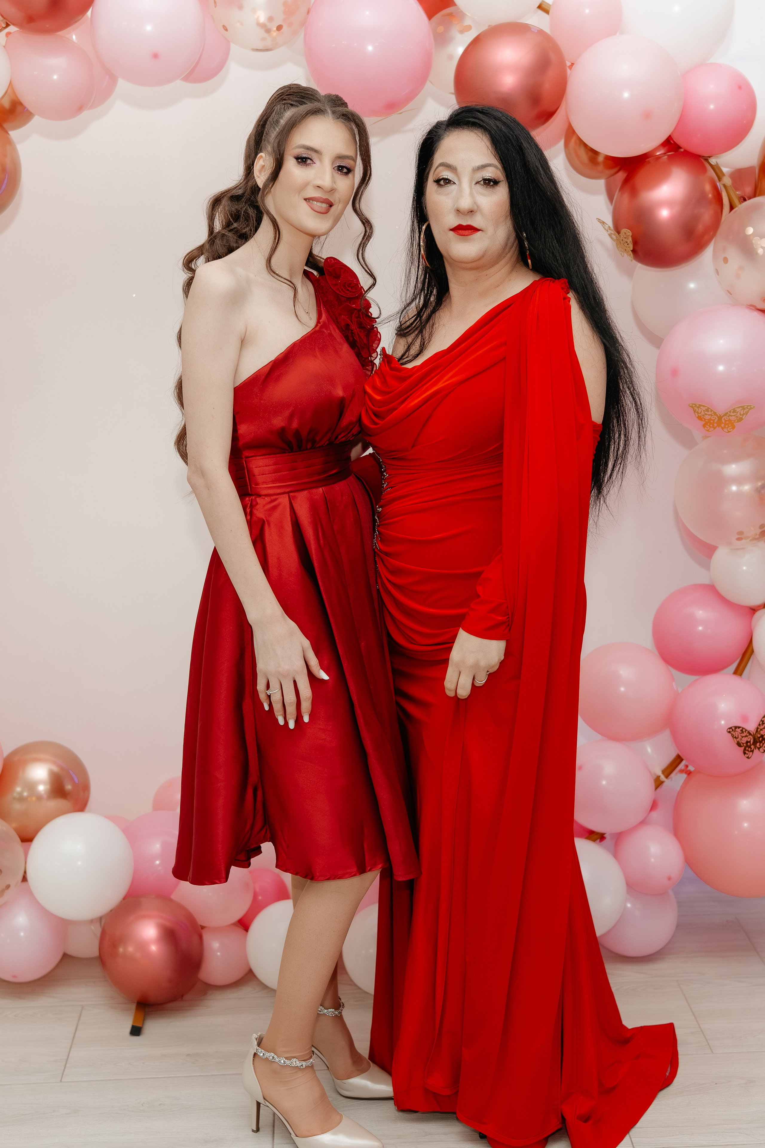 Petrecerea de botez la Restaurantul Silmat din Bălăbănești, Galați: mama Maria și nașa, îmbrăcate elegant în roșu, zâmbesc fericite într-un cadru cald și plin de bucurie. Atmosferă festivă și familială.