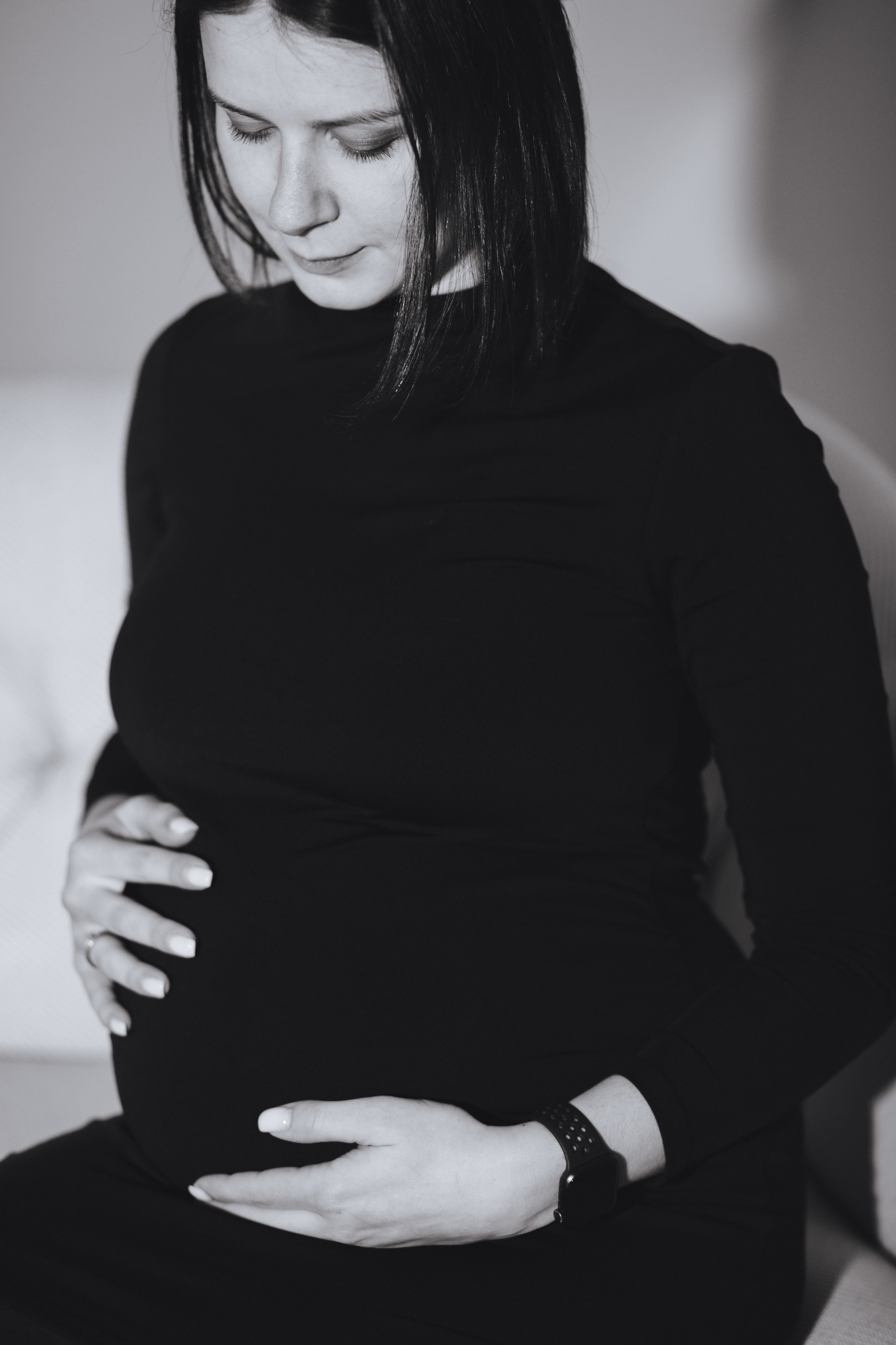 Nachdenkliche schwangere Frau hält liebevoll ihren Babybauch im Fotostudio.