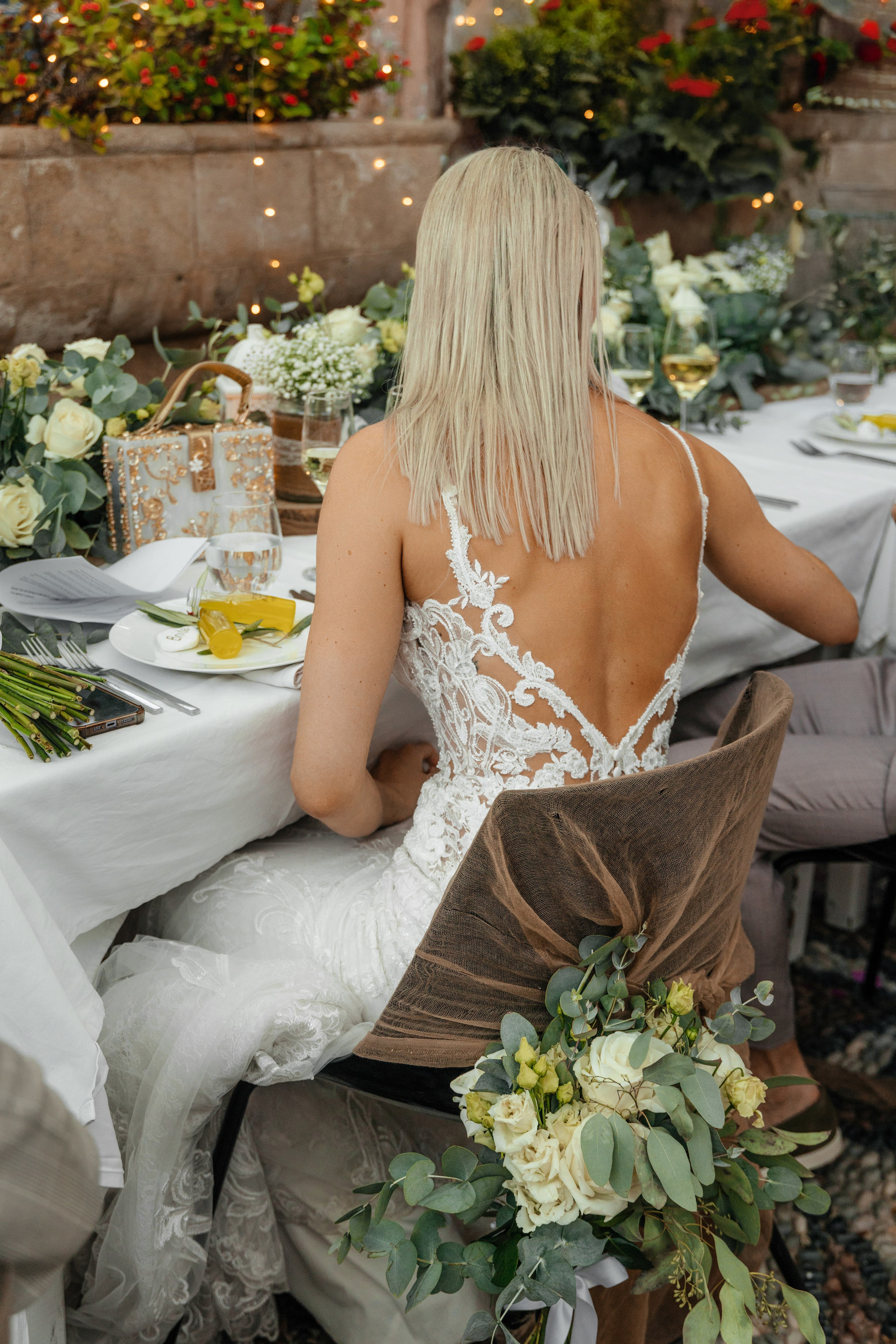Bride is sitting at the table at a rustic bar in Lindos, Greece.