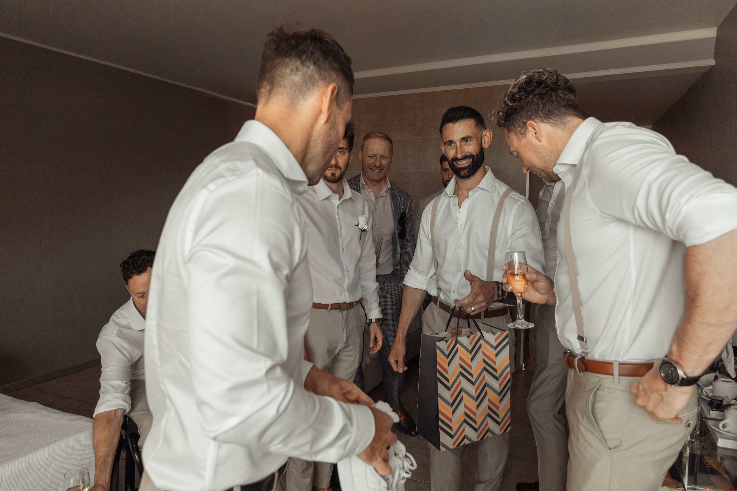 Group of friends are giving a gift to a Groom and laughing in a charming Sheraton hotel, Rhodes, Greece