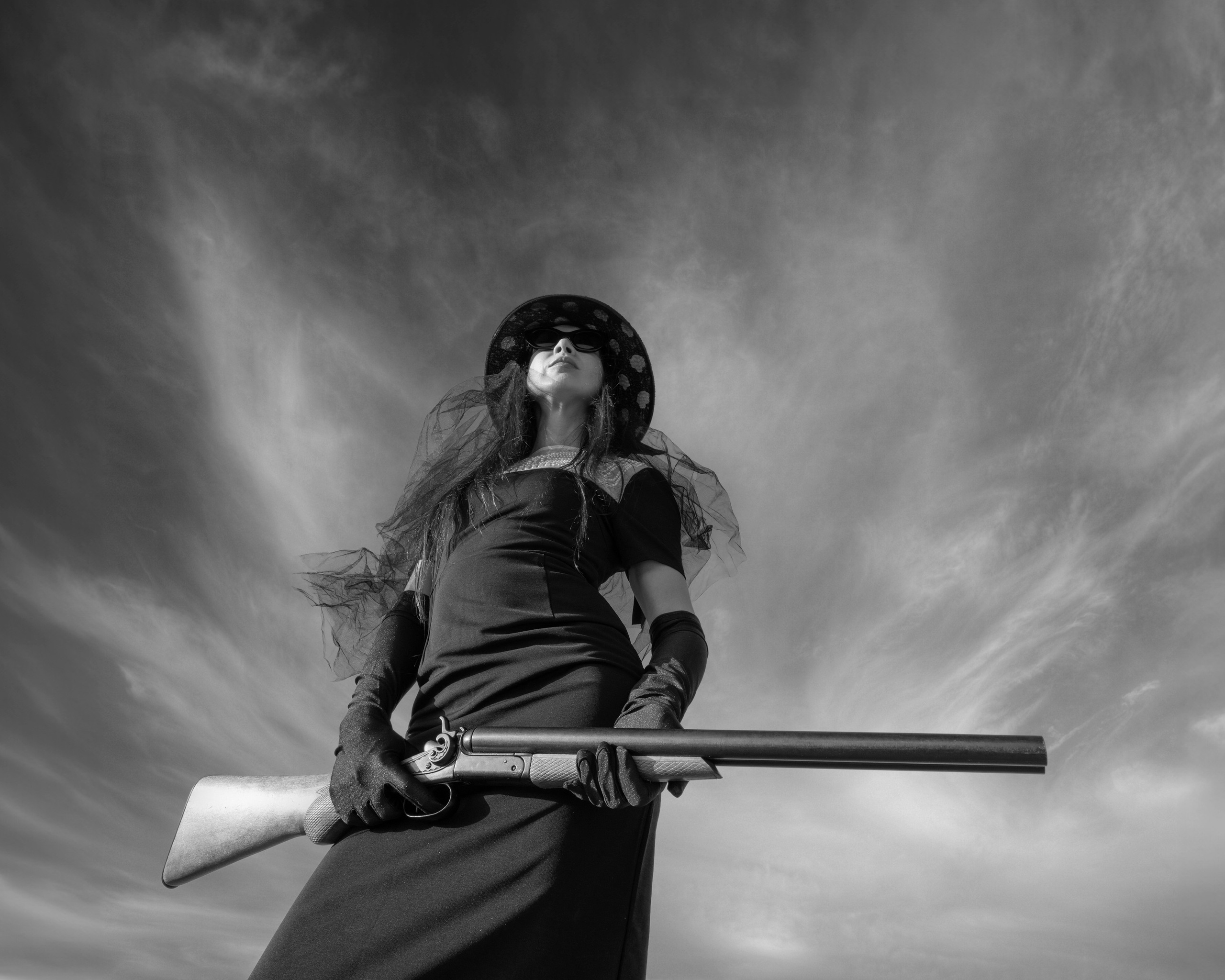 Conceptual female portrait with gun, cinematic black and white style