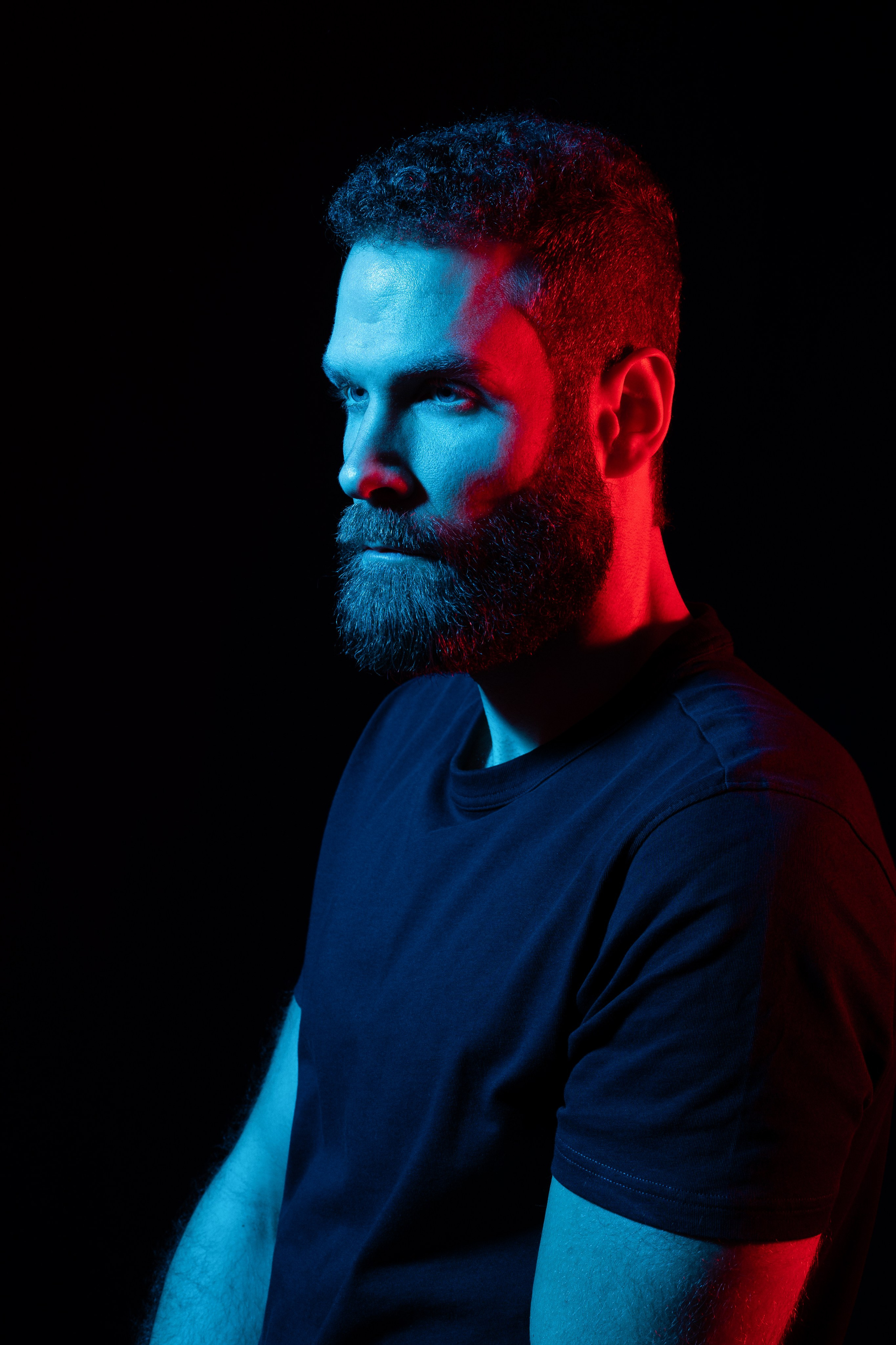 Maskulines Männerporträt im Low-Key-Stil mit farbigem Licht im Studio