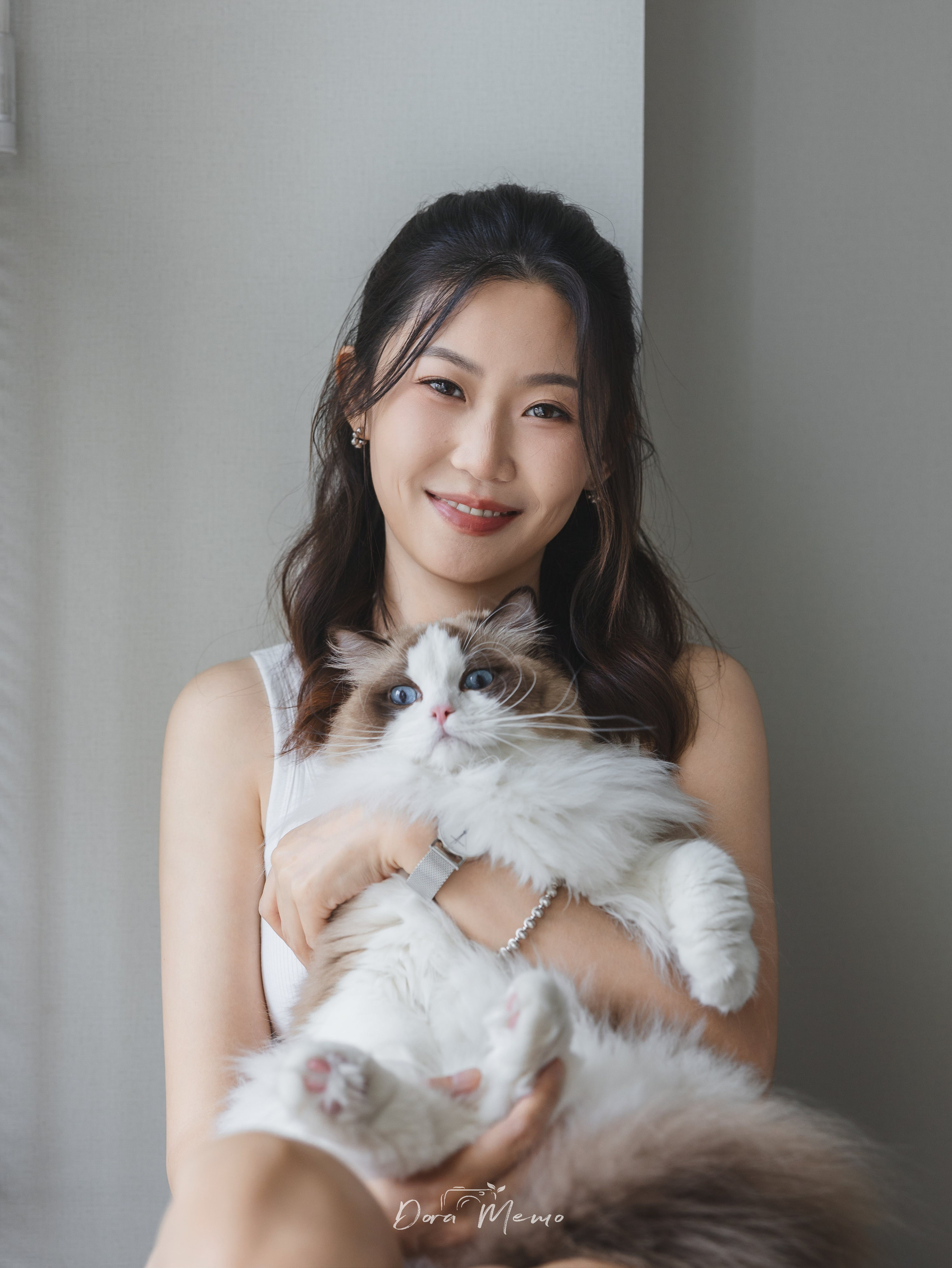 A smiling woman holds her ragdoll cat in a clean, softly lit room — an intimate portrait captured by a Shanghai family lifestyle photographer.