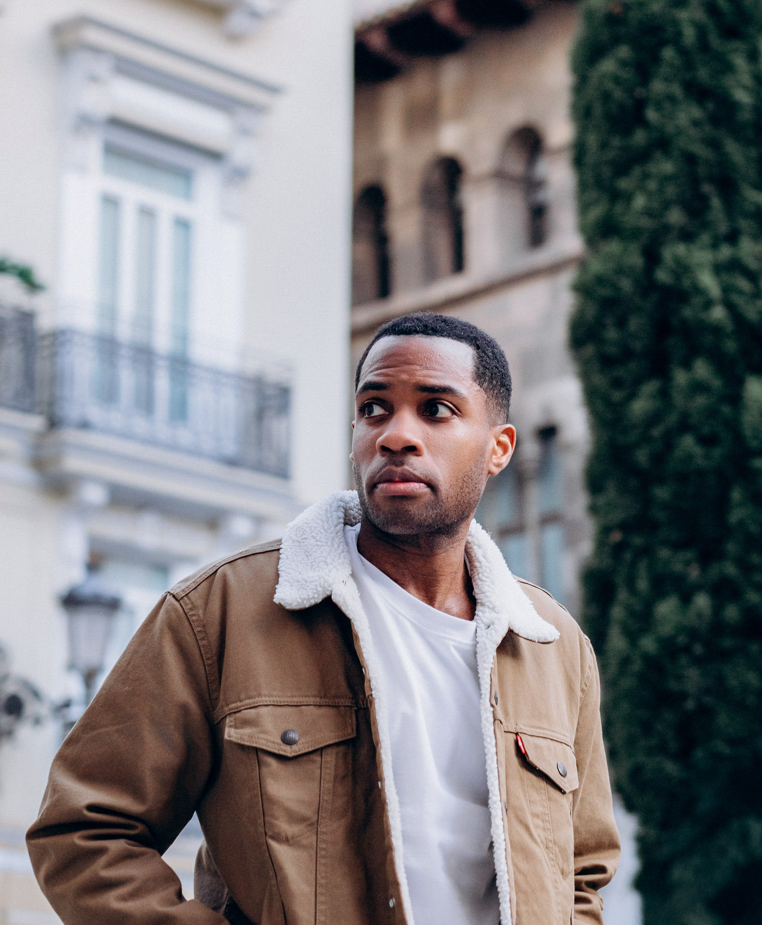 Мужская портретная фотосессия в Валенсии, Испания, с участием стильного и уверенного мужчины, снятого в историческом городском пространстве, в повседневной куртке и белой рубашке, с мягким естественным светом, малой глубиной резкости и элегантной средиземноморской архитектурой на фоне — идеально для мужской портретной фотографии, lifestyle-фотосессий для мужчин, портретов для персонального бренда, профессиональных хедшотов и мужских фотосессий в Валенсии и по всей Испании.