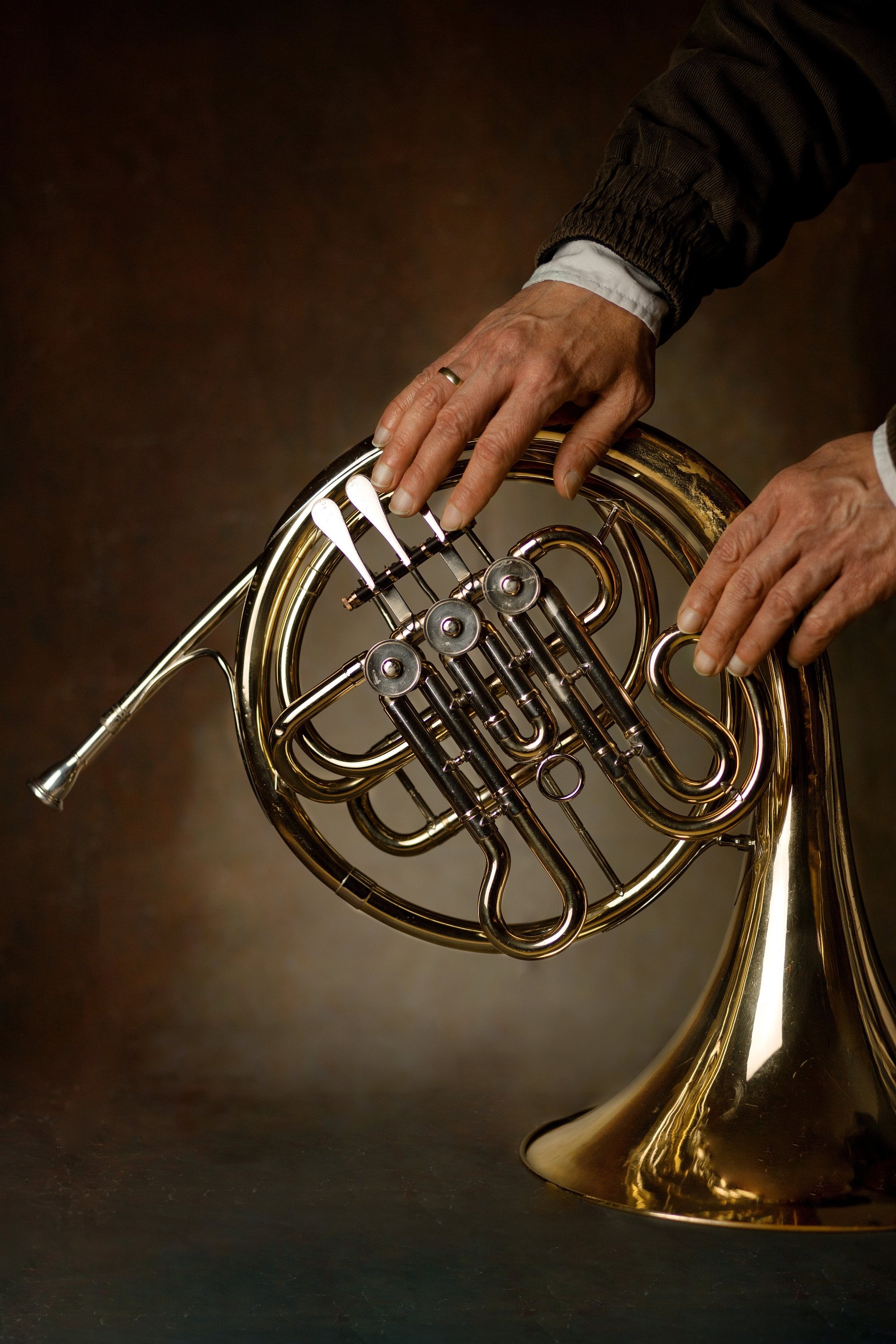 Hände auf einem Waldhorn auf dunklem Hintergrund
