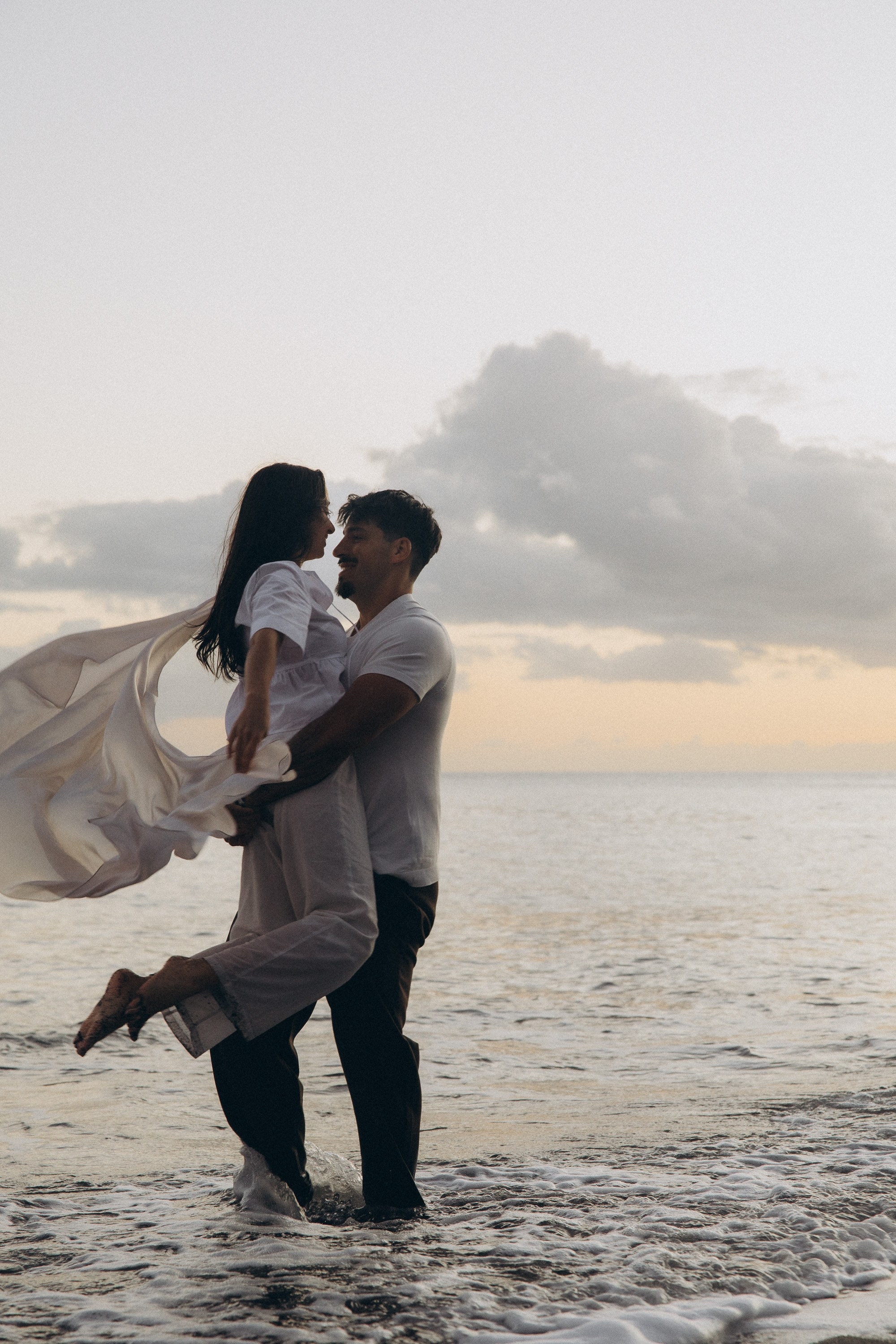 Couple sharing a romantic moment during sunset on Madeira Island, with the ocean and cliffs in the background