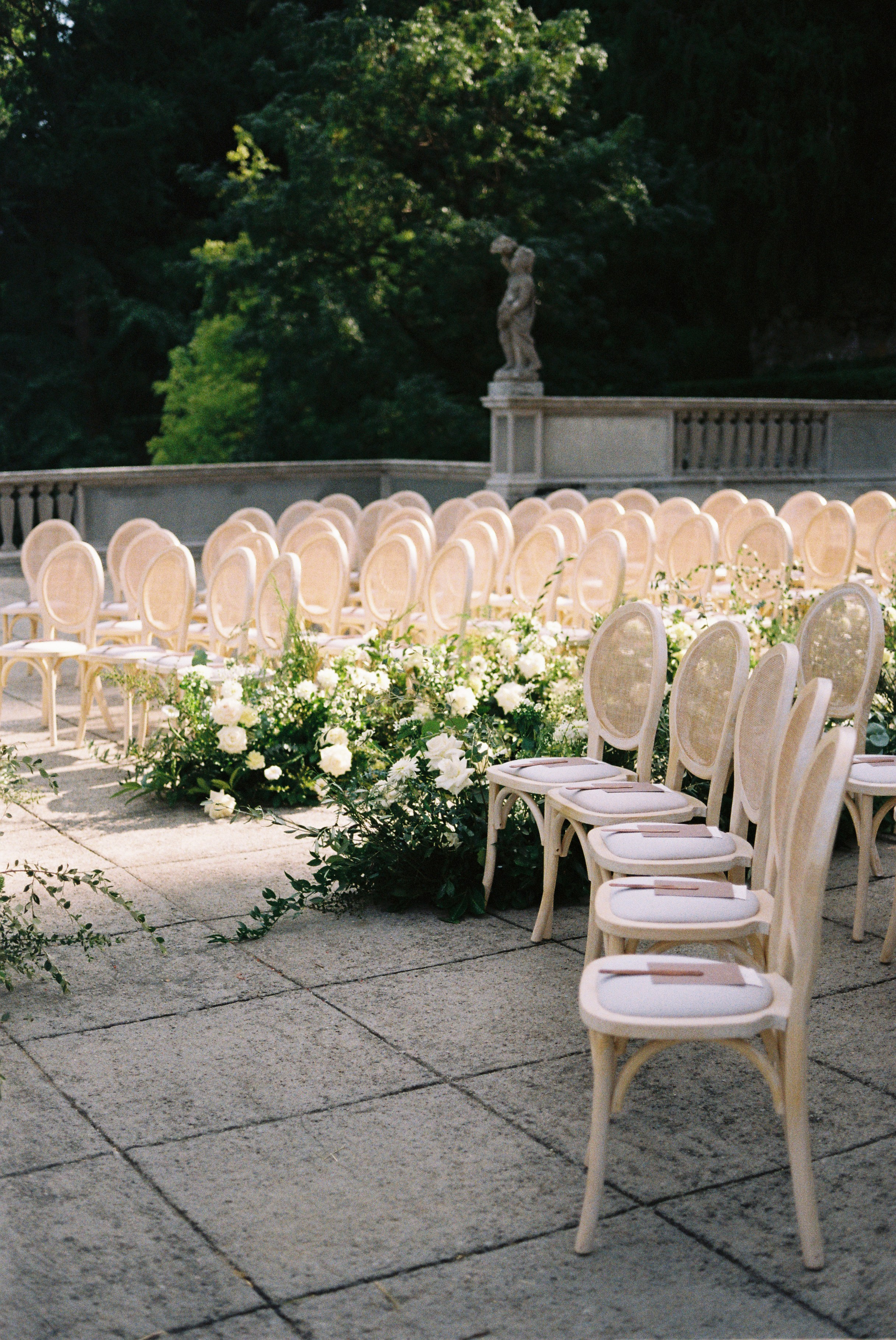 Elegant outdoor wedding seating arranged with soft chairs and white floral accents in sunny garden.