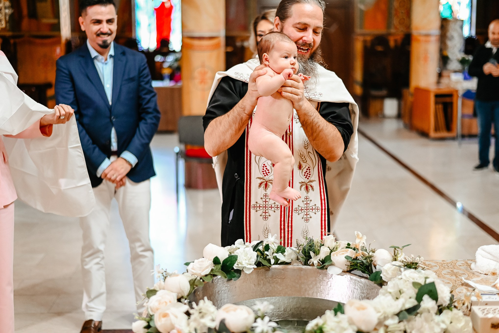 Copil în brațele preotului lângă cristelniță – cadru din ceremonia de botez Ana Maria Drăgan