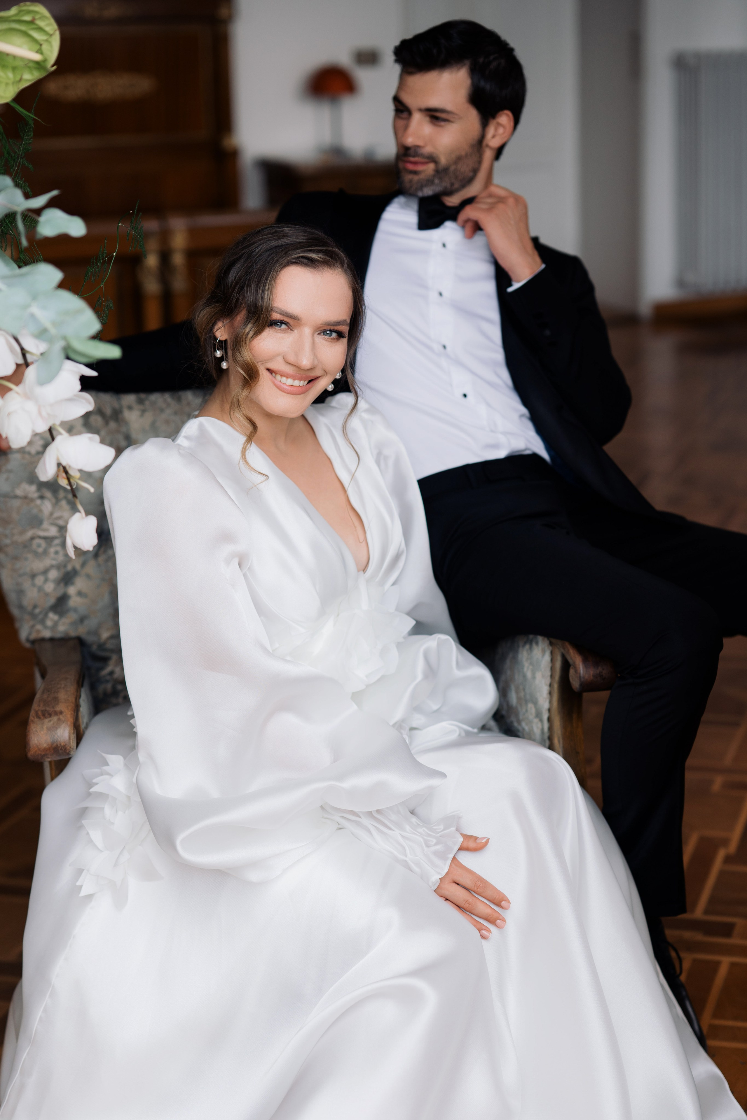 a man in a suit sitting next to a woman in a white dress
