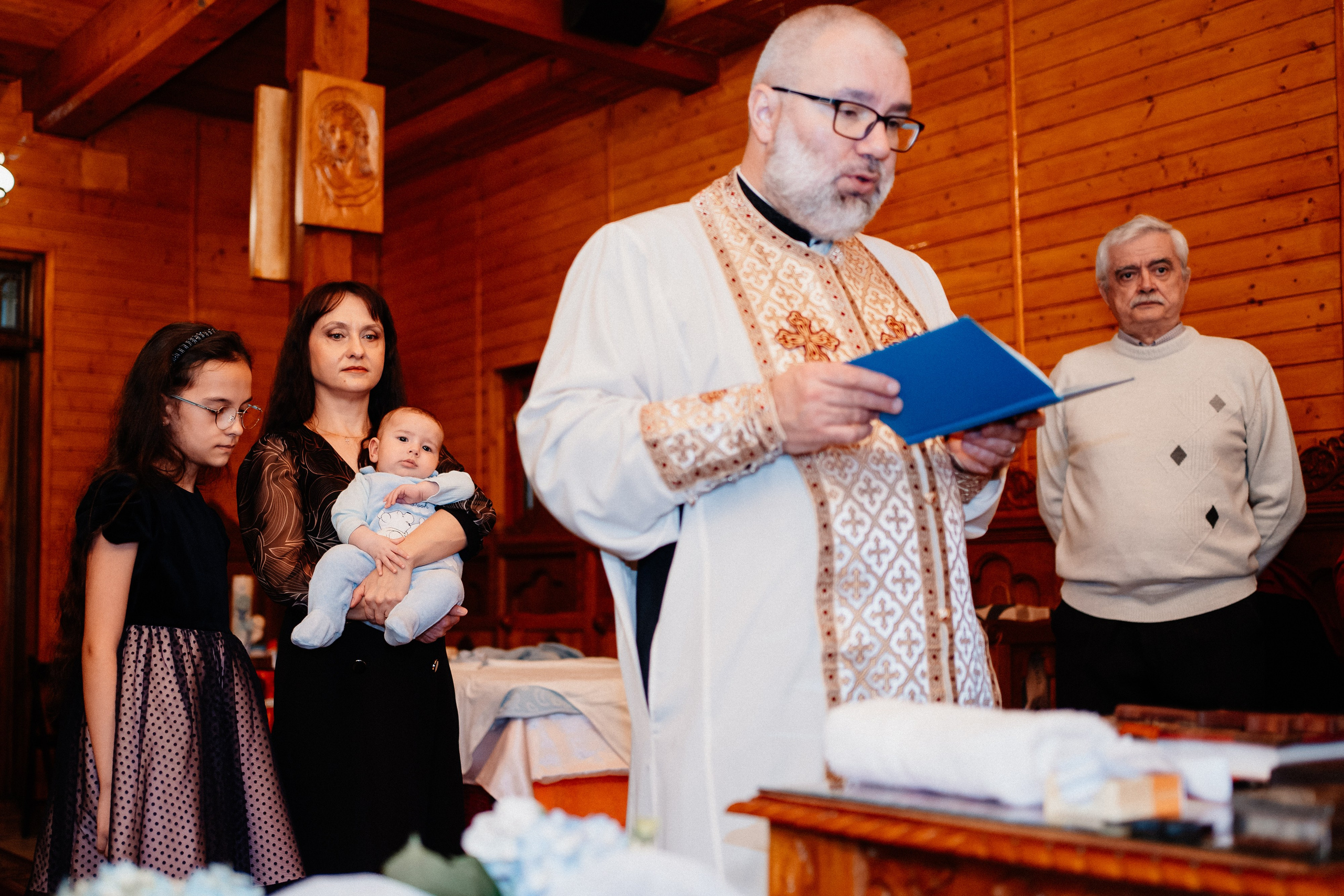 Instantaneu plin de tandrețe dintre părinți și bebeluș în ziua botezului, realizat în Bucuresti. Fotografie profesională de botez, capturând emoțiile autentice ale familiei într-un decor luminos și cald