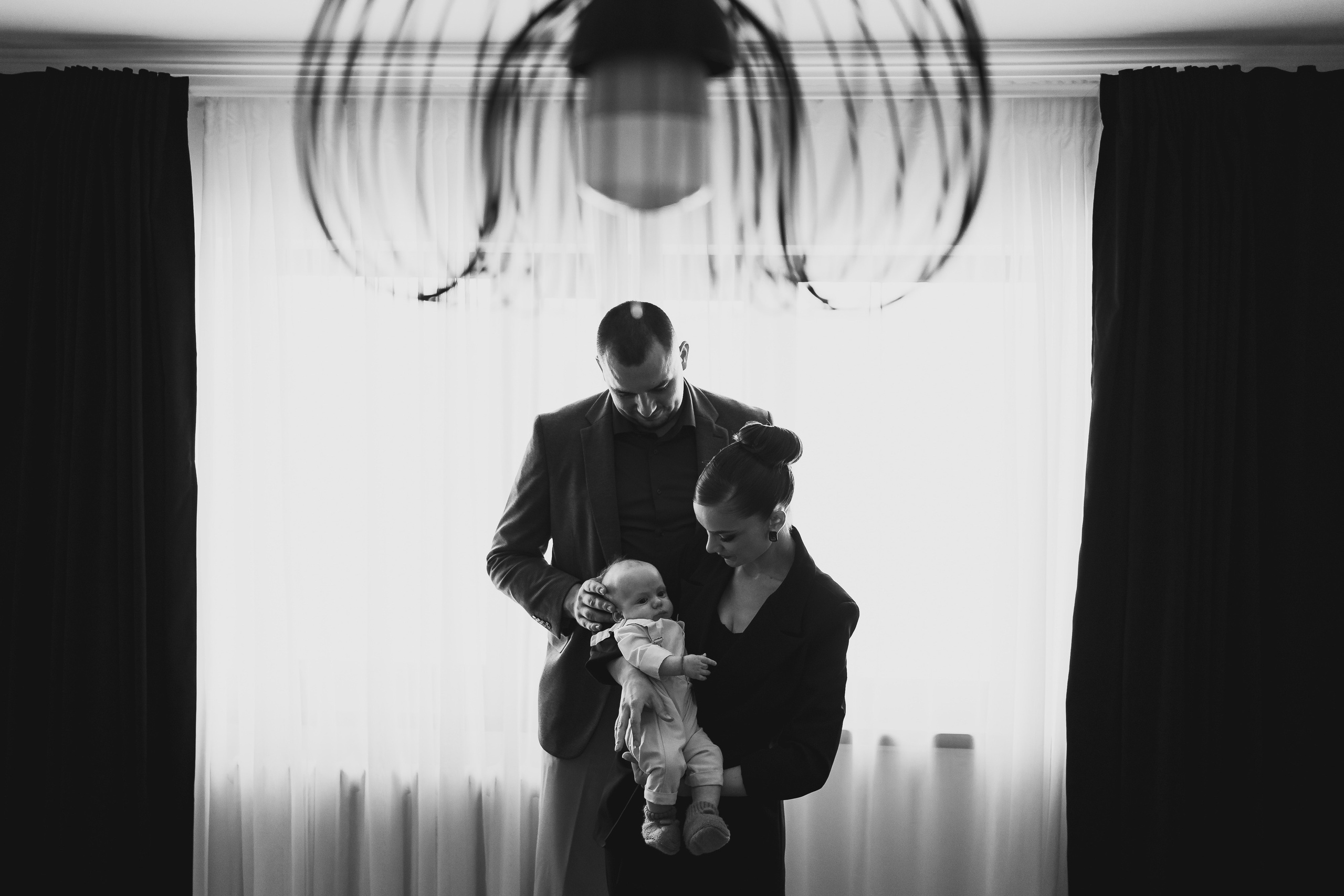 Instantaneu plin de tandrețe dintre părinți și bebeluș în ziua botezului, realizat în Craiova. Fotografie profesională de botez, capturând emoțiile autentice ale familiei într-un decor luminos și cald