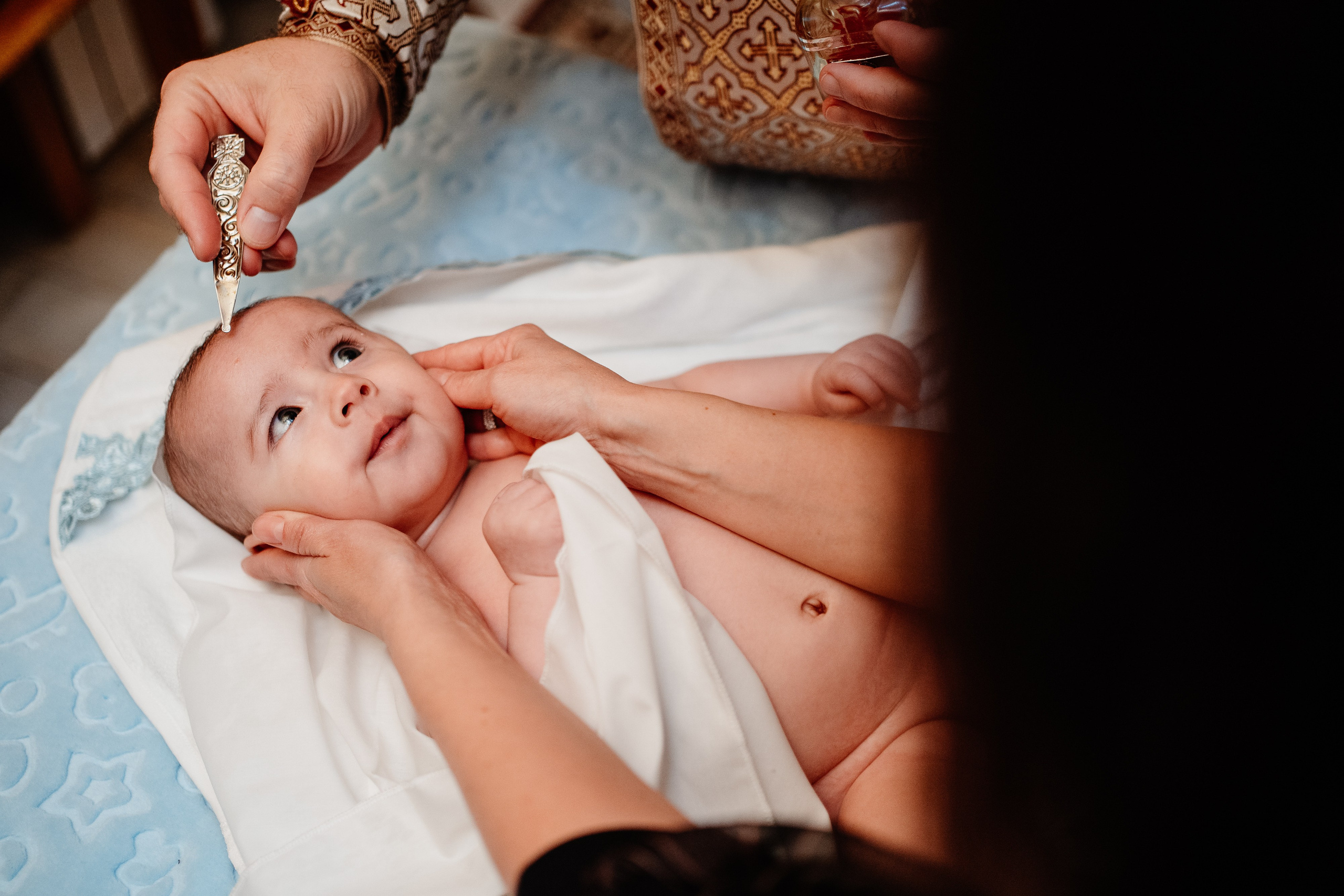 Instantaneu plin de tandrețe dintre părinți și bebeluș în ziua botezului, realizat în Bucuresti. Fotografie profesională de botez, capturând emoțiile autentice ale familiei într-un decor luminos și cald
