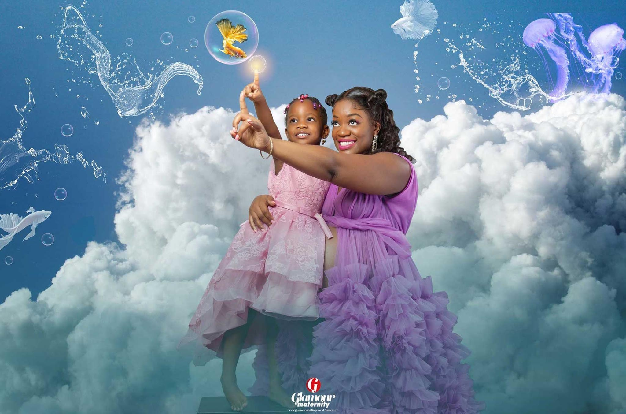 Whimsical maternity portrait of a pregnant mother holding her young daughter among soft clouds and fantasy water effects.