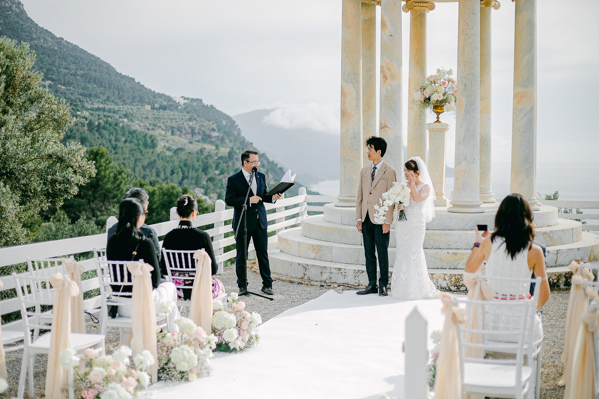 Wedding officiant leading the ceremony as bride and groom stand together at Son Marroig
