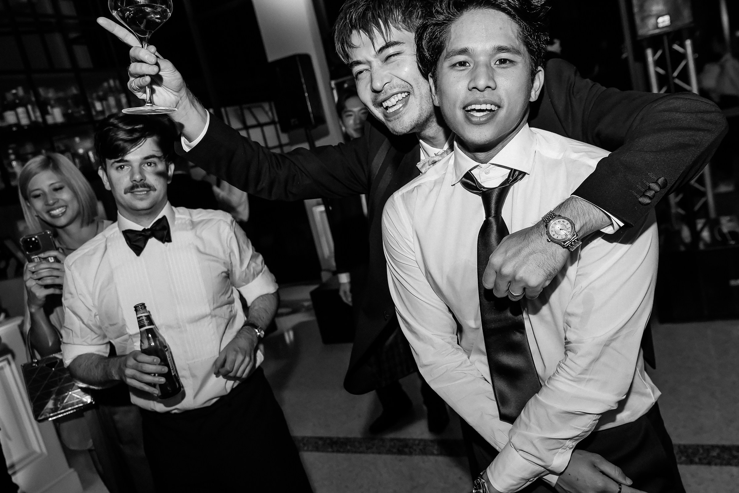 Two well-dressed men in tuxedos and ties enjoying the party. 