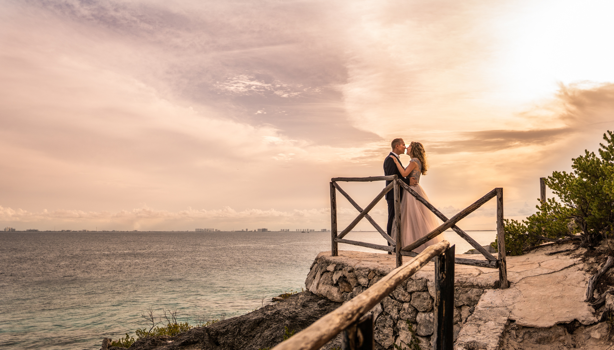 Elegant couple posing on cliff at sunset in Isla Mujeres